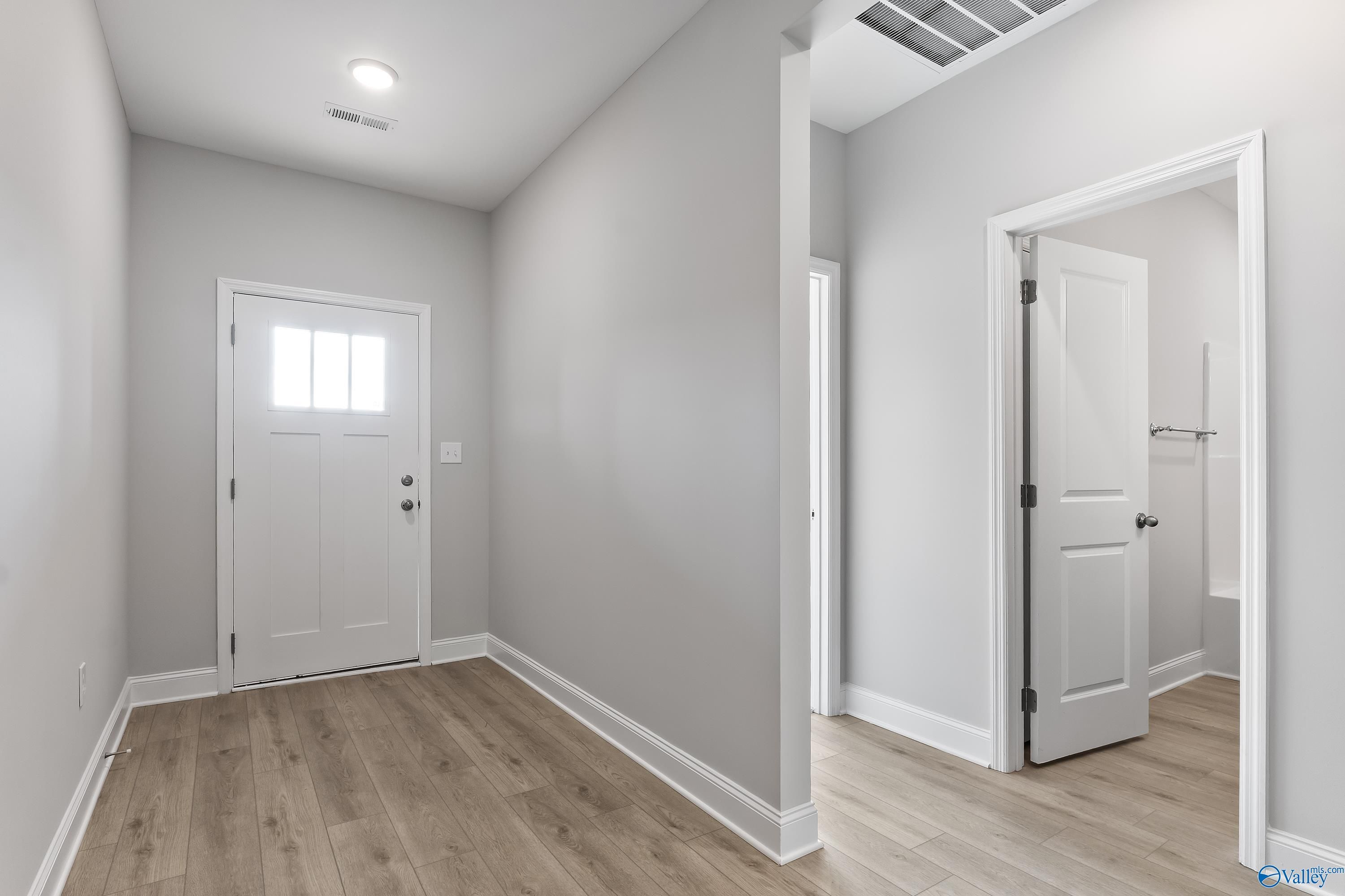 Bright hallway with gray walls, hardwood floors, and white doors in Davidson Homes The Daphne C, Huntsville, Alabama