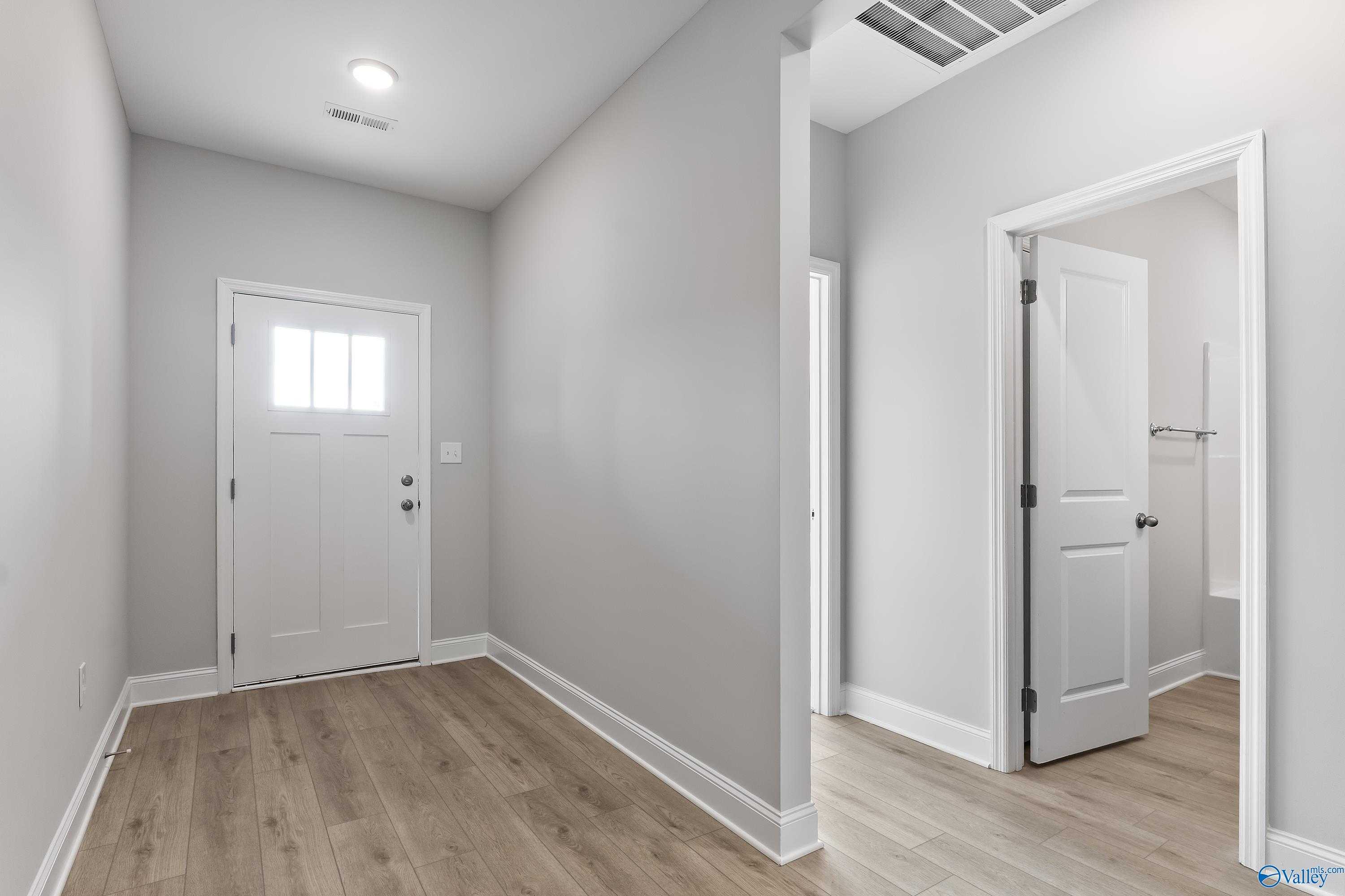 Bright hallway with gray walls, hardwood floors, and white doors in Davidson Homes The Daphne C, Huntsville, Alabama