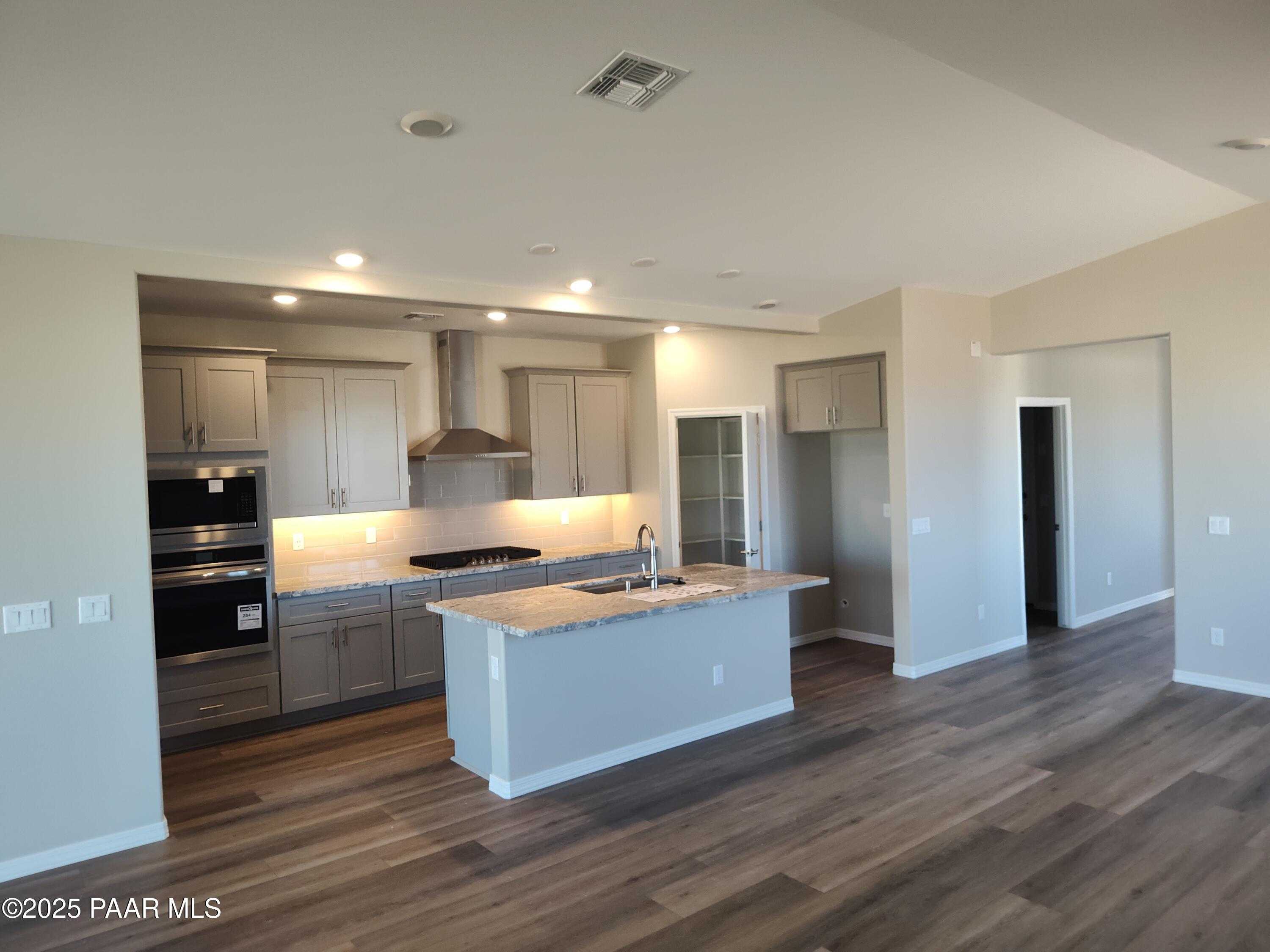 Modern open-concept kitchen with gray shaker cabinets, large island sink, stainless appliances in Davidson Homes The Frontier C, Prescott Valley, AZ
