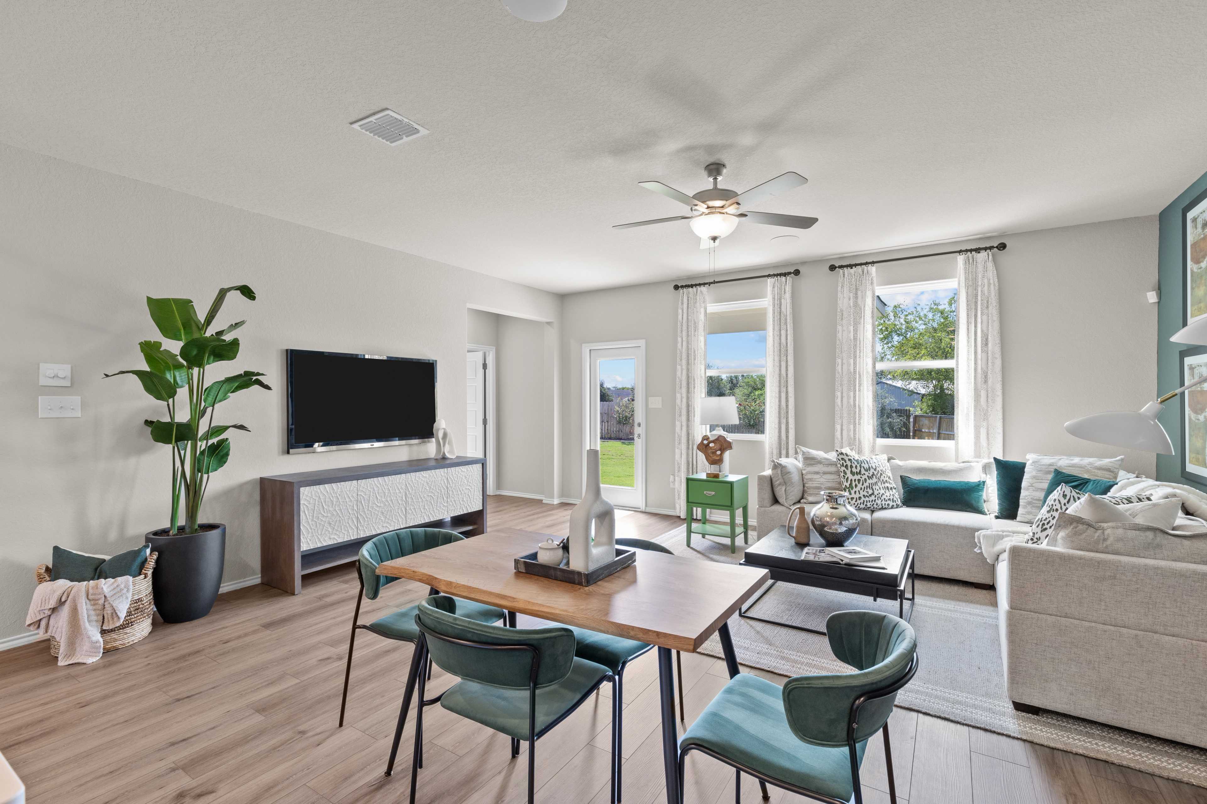 Open-concept living and dining room at Comanche Ridge in San Antonio TX by Davidson Homes featuring hardwood floors, beige sofa, and large windows