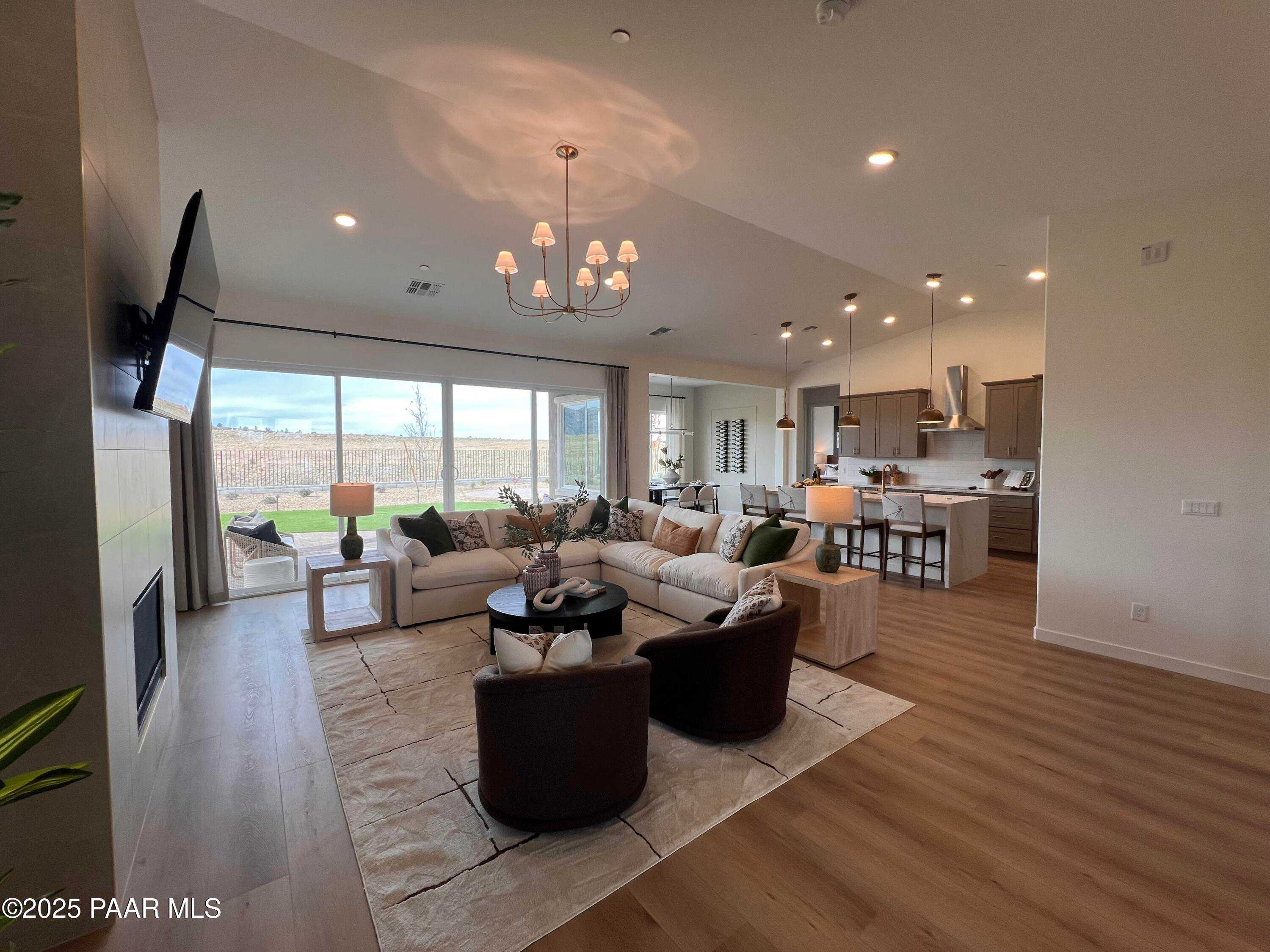 Open-concept living room with white sectional sofa, gas fireplace, and adjacent kitchen in Davidson Homes The Blaze D, Prescott, Arizona