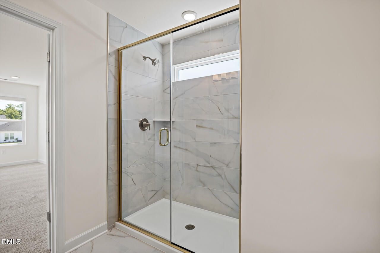 Modern marble-tile walk-in shower with gold-framed glass door in Davidson Homes Hickory II B bathroom, Lillington NC
