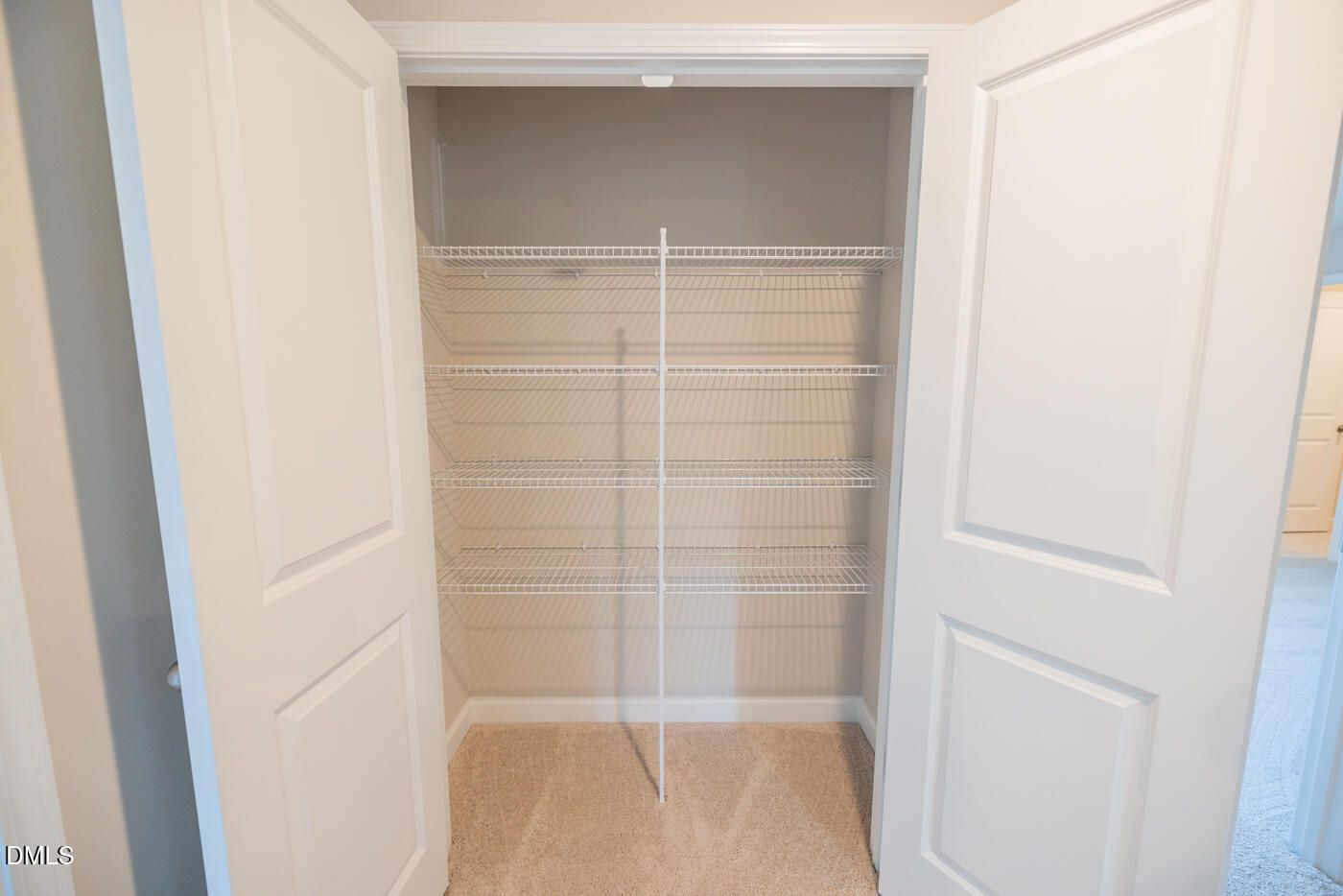 Spacious walk-in closet with wire shelving, central hanging rod, and open double doors in Davidson Homes The Hickory II C, Zebulon, NC