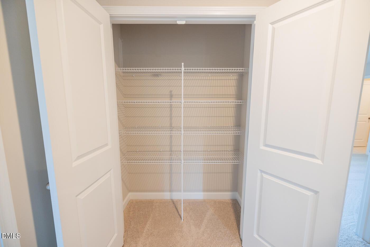 Spacious walk-in closet with wire shelving, central hanging rod, and open double doors in Davidson Homes The Hickory II C, Zebulon, NC