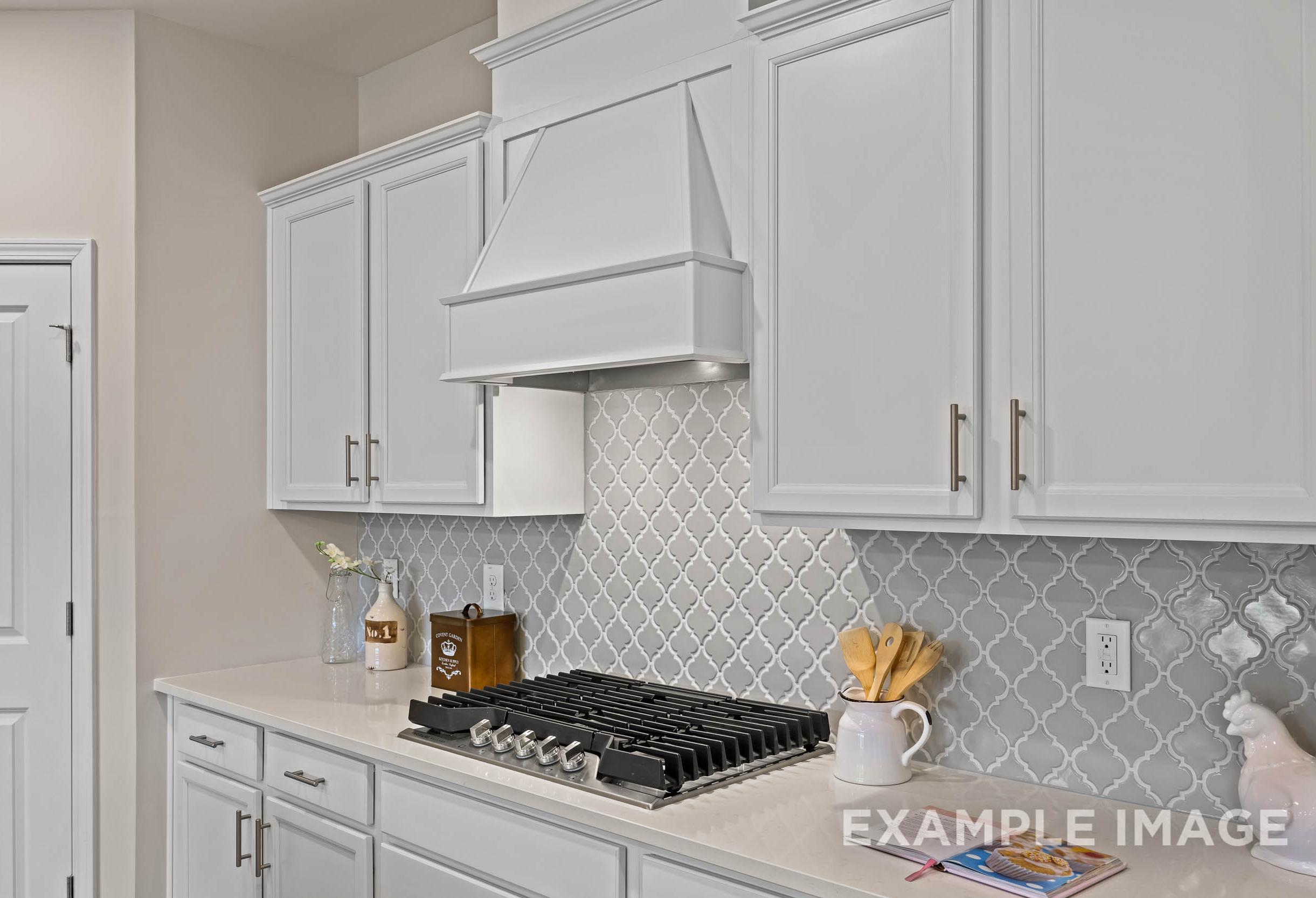 Modern white shaker kitchen in The Preston A featuring gas range, herringbone backsplash, and open counters