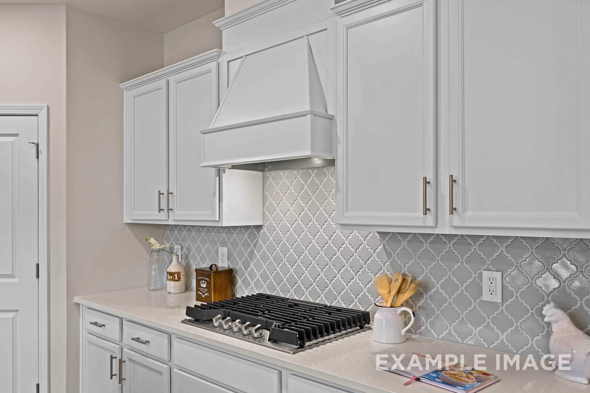 Spacious white kitchen in The Preston B by Davidson Homes featuring shaker cabinets, gas range, and herringbone tile backsplash