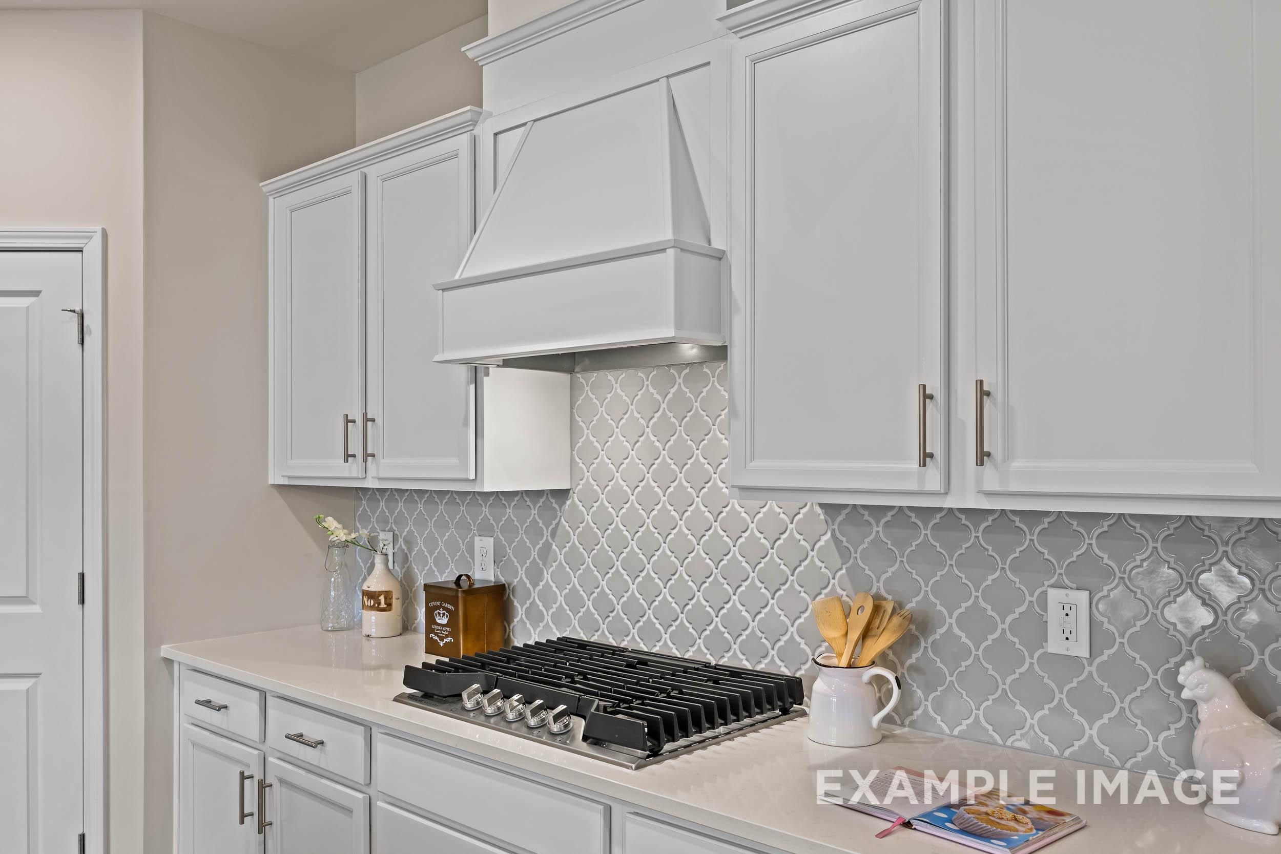 Spacious white kitchen in The Preston B by Davidson Homes featuring shaker cabinets, gas range, and herringbone tile backsplash