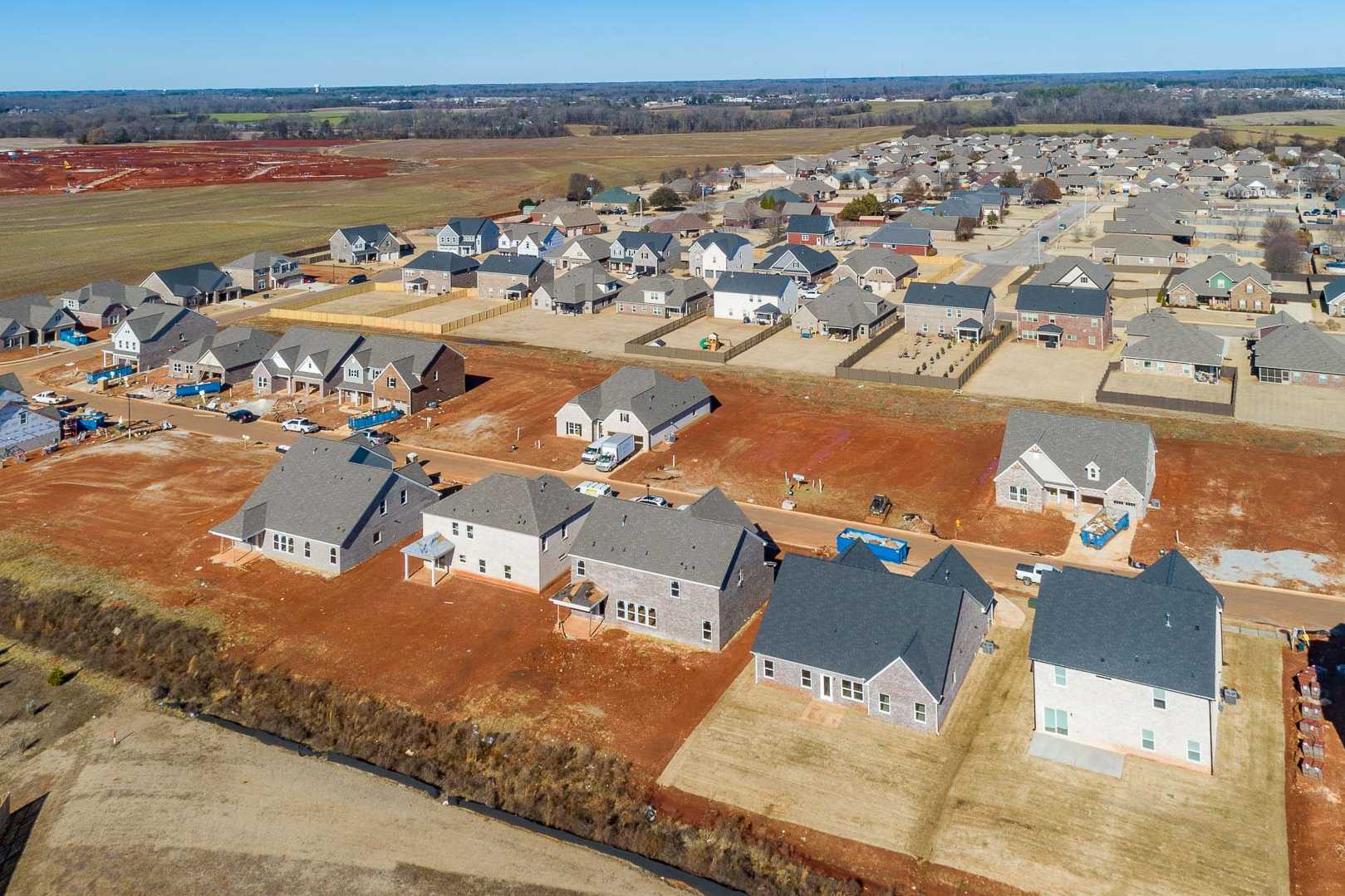 Aerial view of new homes under construction in Old Stone Athens Alabama by Davidson Homes on red clay lots amid fields
