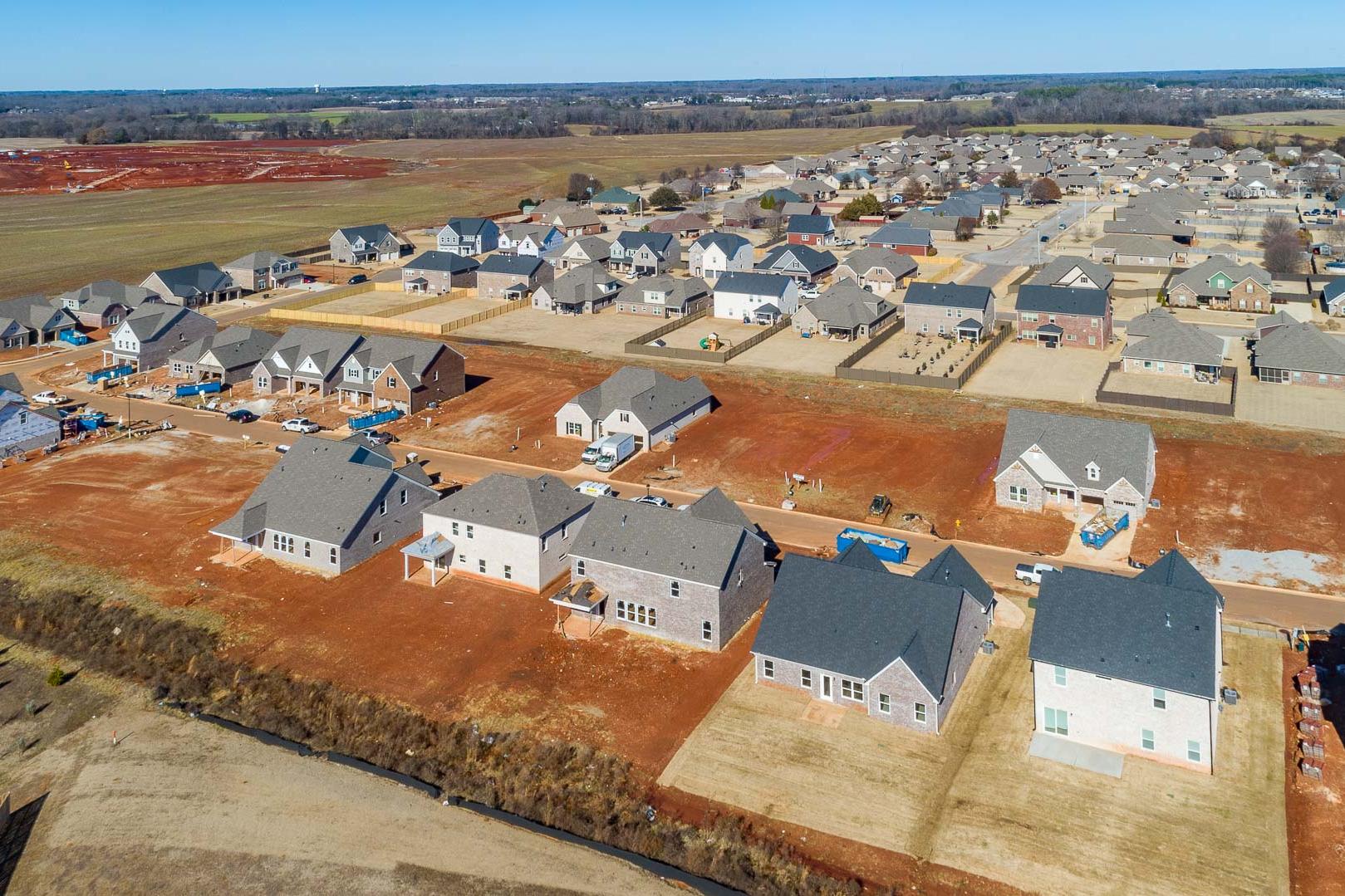 Aerial view of new homes under construction in Old Stone Athens Alabama by Davidson Homes on red clay lots amid fields