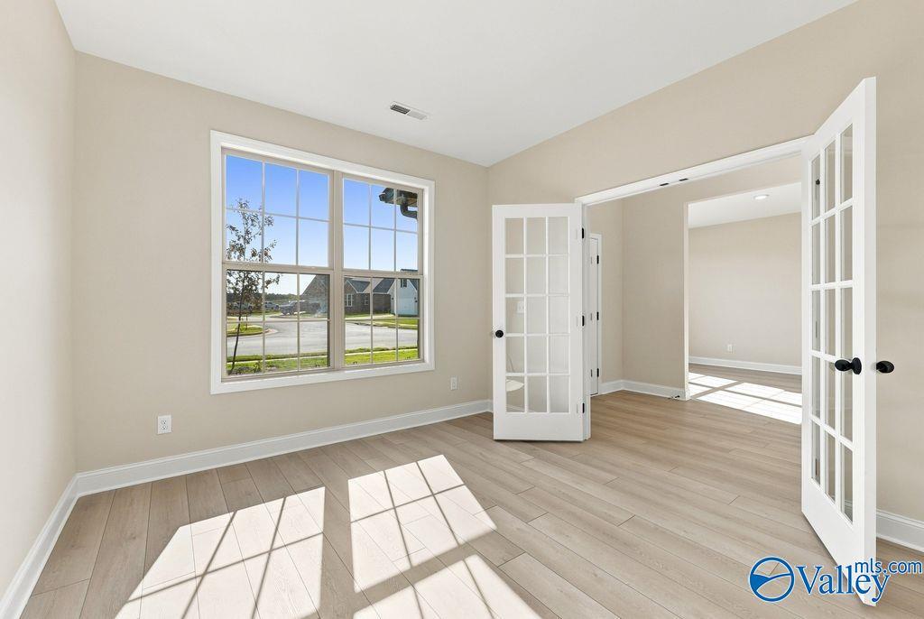 Bright home office or bedroom with French doors and light wood floors in The Madison A floor plan, Cain Park, Hartselle.