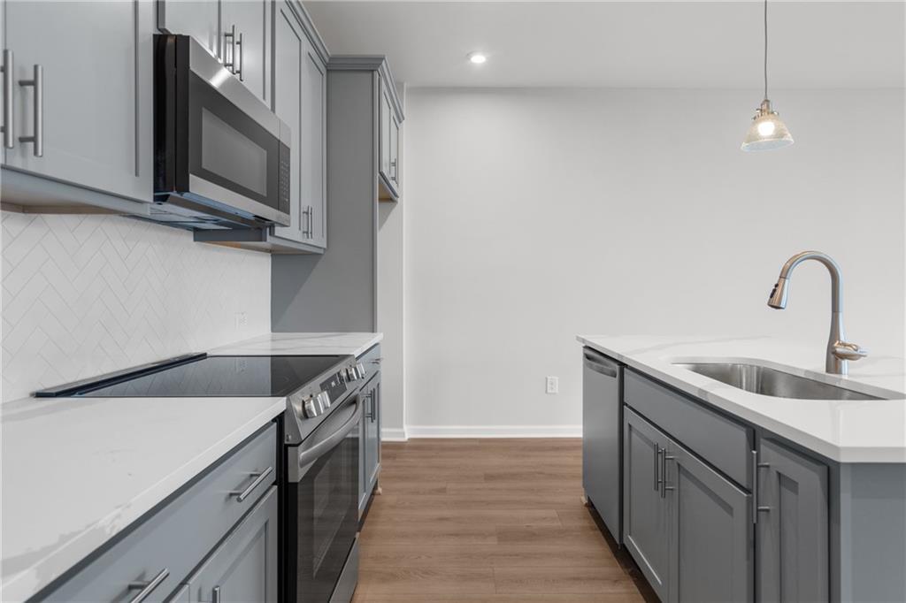 Modern kitchen featuring gray cabinets, white quartz counters, subway tile backsplash, stainless appliances in The Monroe B, Emerson, GA