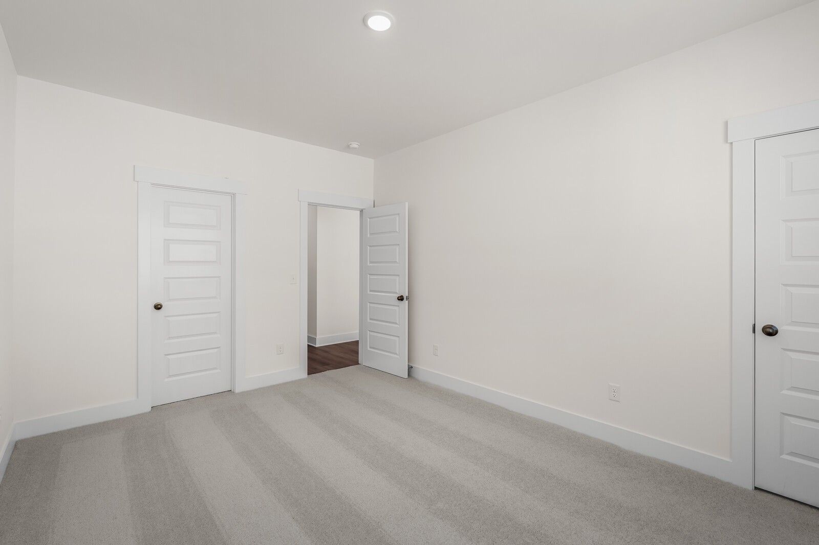 Spacious bedroom with grey carpet and white doors in The Willow floor plan by Davidson Homes in Gallatin, Tennessee.