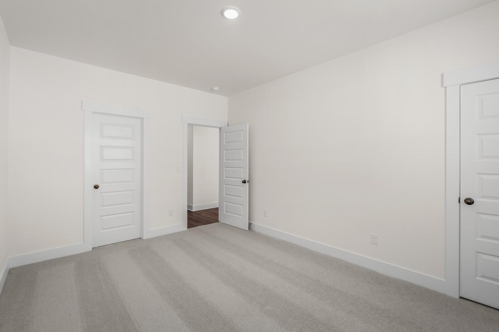 Spacious bedroom with grey carpet and white doors in The Willow floor plan by Davidson Homes in Gallatin, Tennessee.