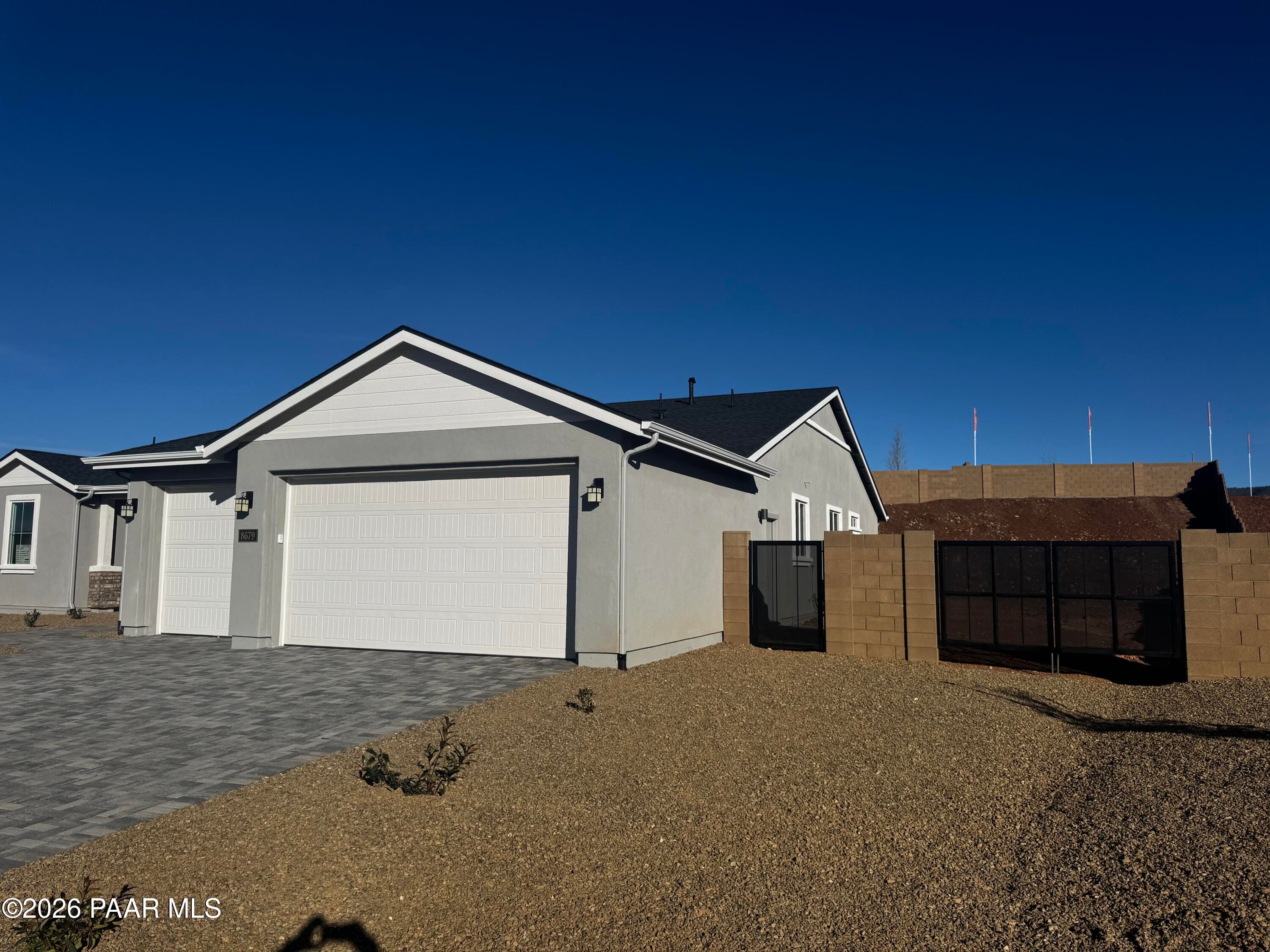 Modern gray single-story home with 3-car garage, paver driveway, and desert yard in Morningstar, Prescott Valley, Arizona