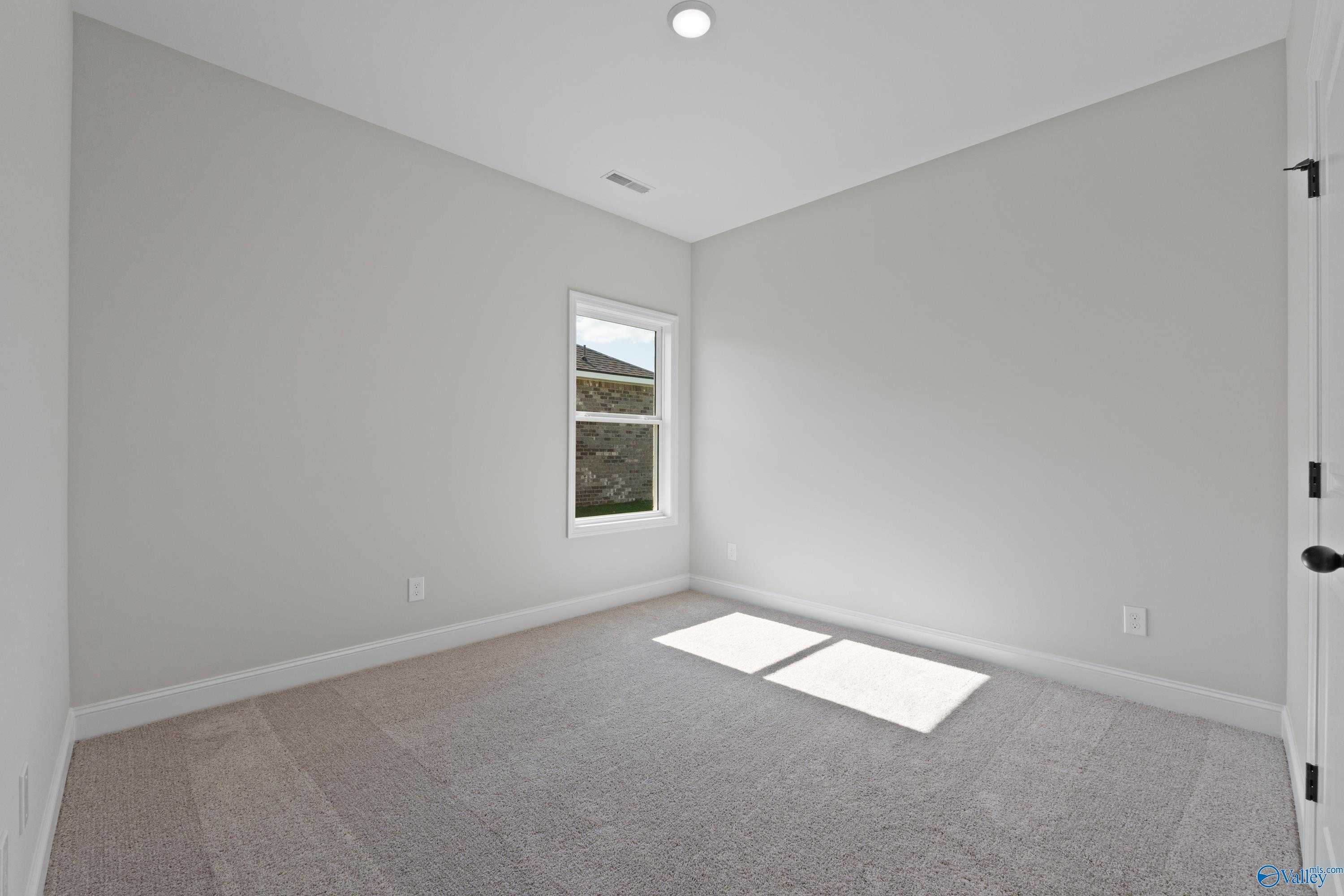 Bright empty bedroom with gray walls, beige carpet, and sunny window in 3-bedroom Franklin C home, Hazel Green, Alabama