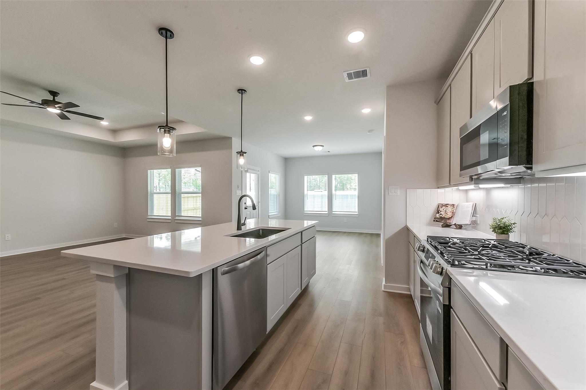 Modern open-concept kitchen featuring white shaker cabinets, quartz island, stainless appliances in Davidson Homes Everett C, Crosby TX