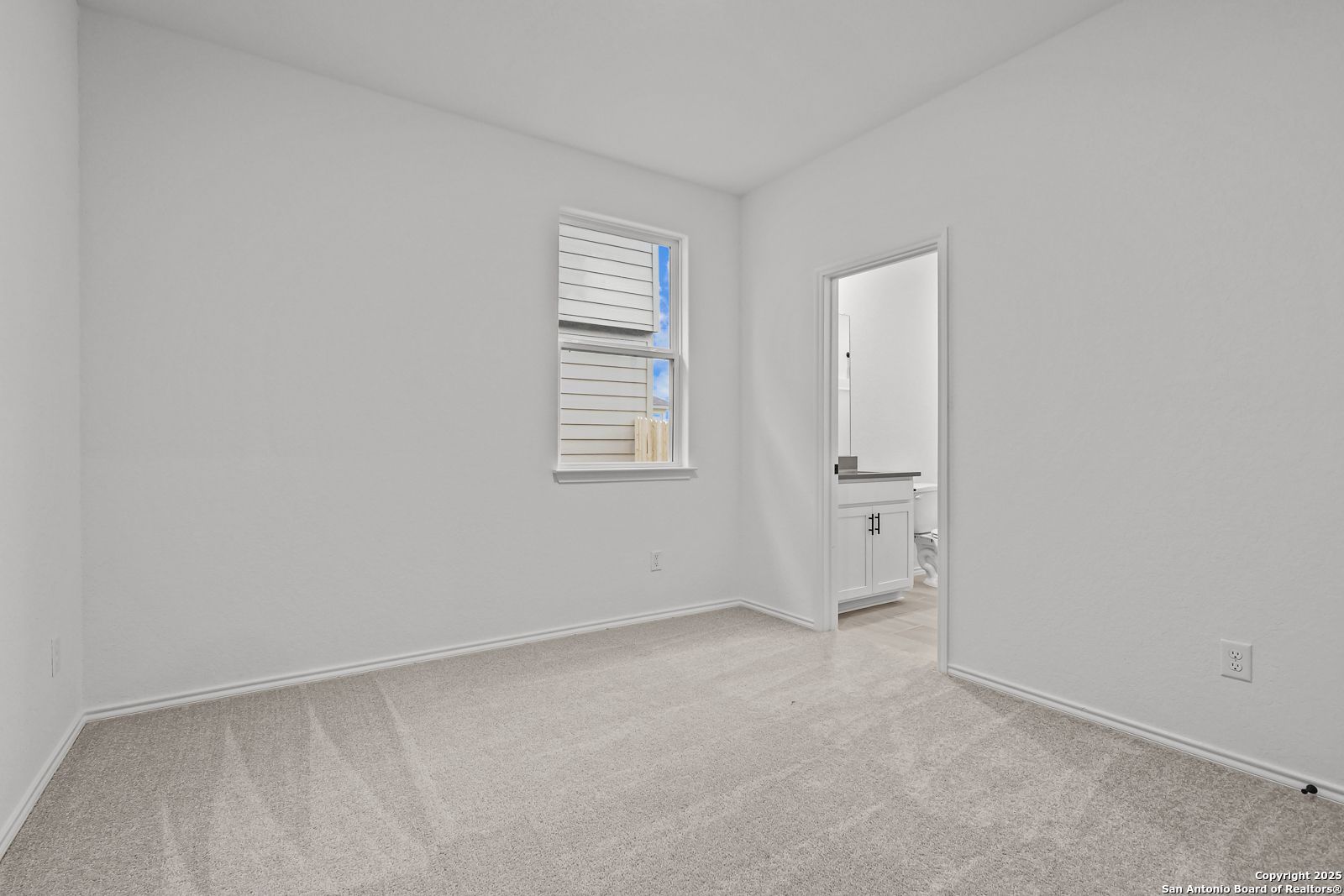 Bright secondary bedroom with attached bath, large window, and plush carpet in Davidson Homes The Daphne J, Converse, Texas