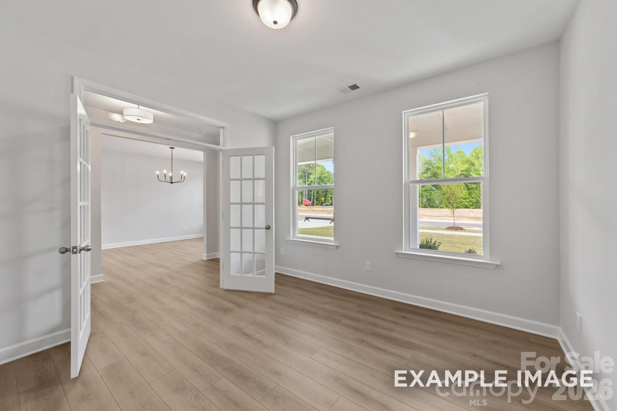 Bright home office with French doors and wood-look flooring in The Magnolia B floor plan at Windgate, Mooresville, NC.