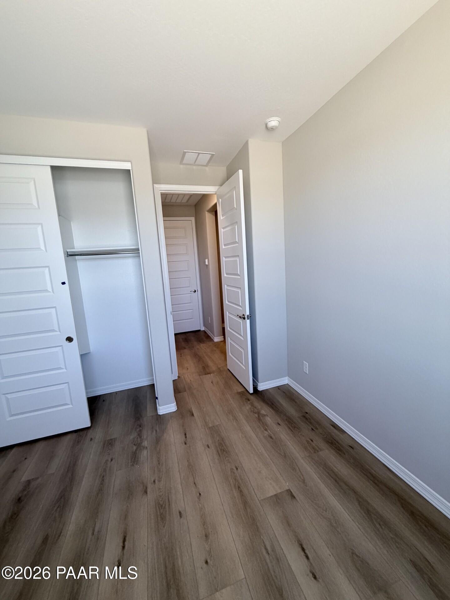 Bedroom with wood-look flooring, walk-in closet, and open doorway in The Frontier A floor plan, Pronghorn Ranch, Prescott.