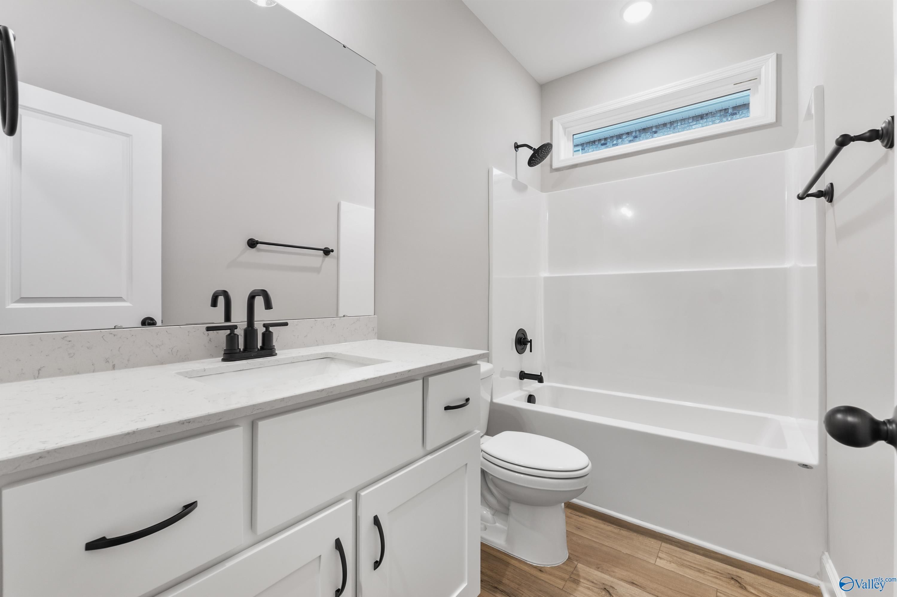 Modern bathroom with white quartz vanity, black fixtures, tub, walk-in shower in Davidson Homes The Asheville C, Meridianville, Alabama