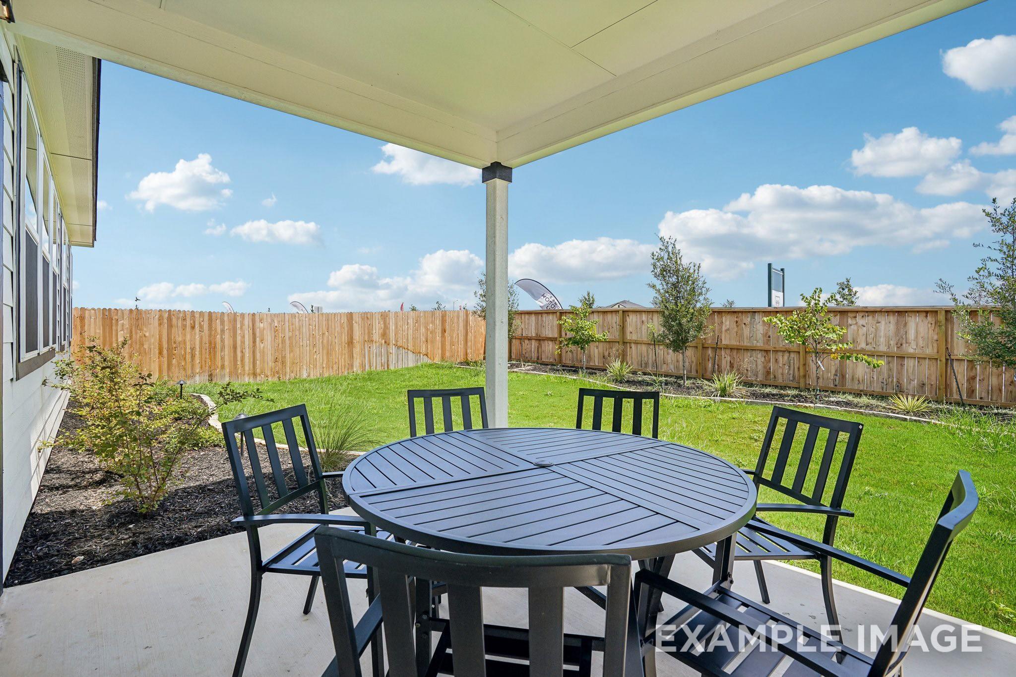 Covered patio with outdoor dining set overlooking fenced backyard at Davidson Homes The Ashport J in Sundance Cove, Crosby, Texas