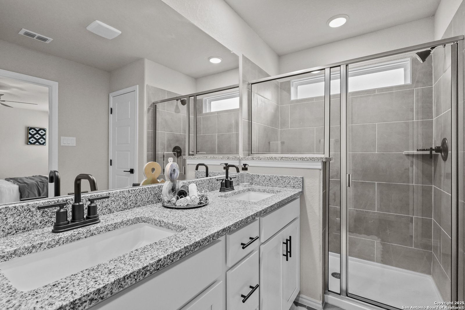 Modern master bathroom featuring double granite vanity, white cabinets, and frameless glass shower in Davidson Homes The Charlotte B, San Antonio