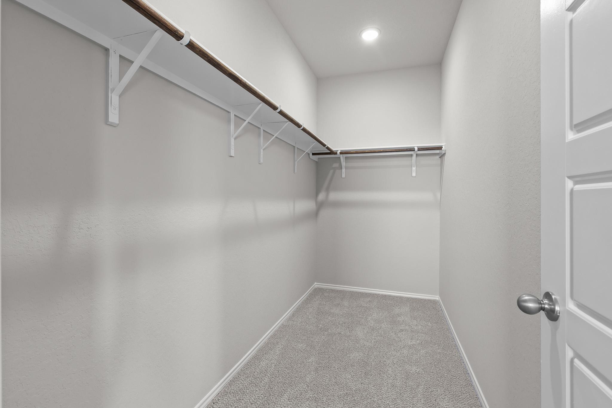 Spacious walk-in closet in the master suite of The Colorado B featuring ample shelving and neutral carpeting.