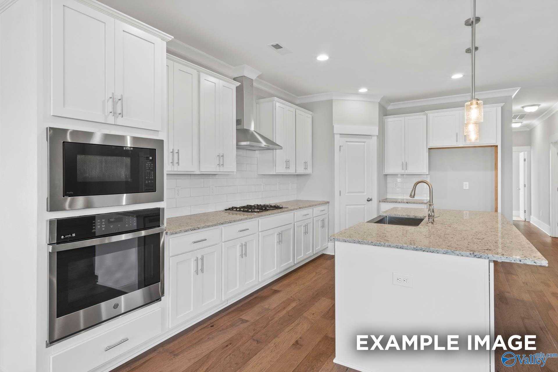 Modern kitchen featuring white shaker cabinets, stainless double oven, granite island sink in Davidson Homes The Rockford, Meridianville, AL