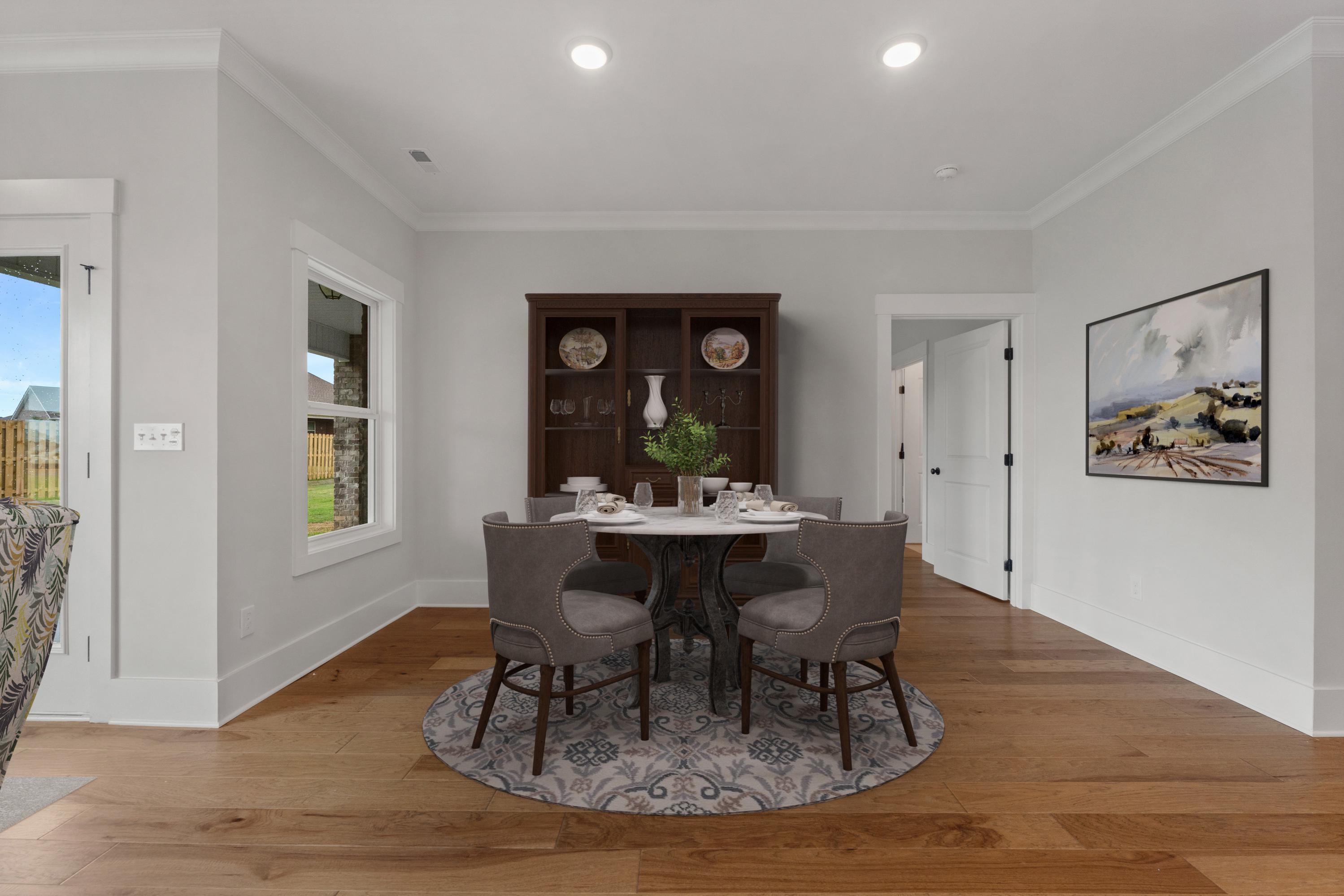Elegant dining room at The Villas at Barnett's Crossing in Madison, Alabama with round table, upholstered chairs, hardwood floors, and buffet cabinet