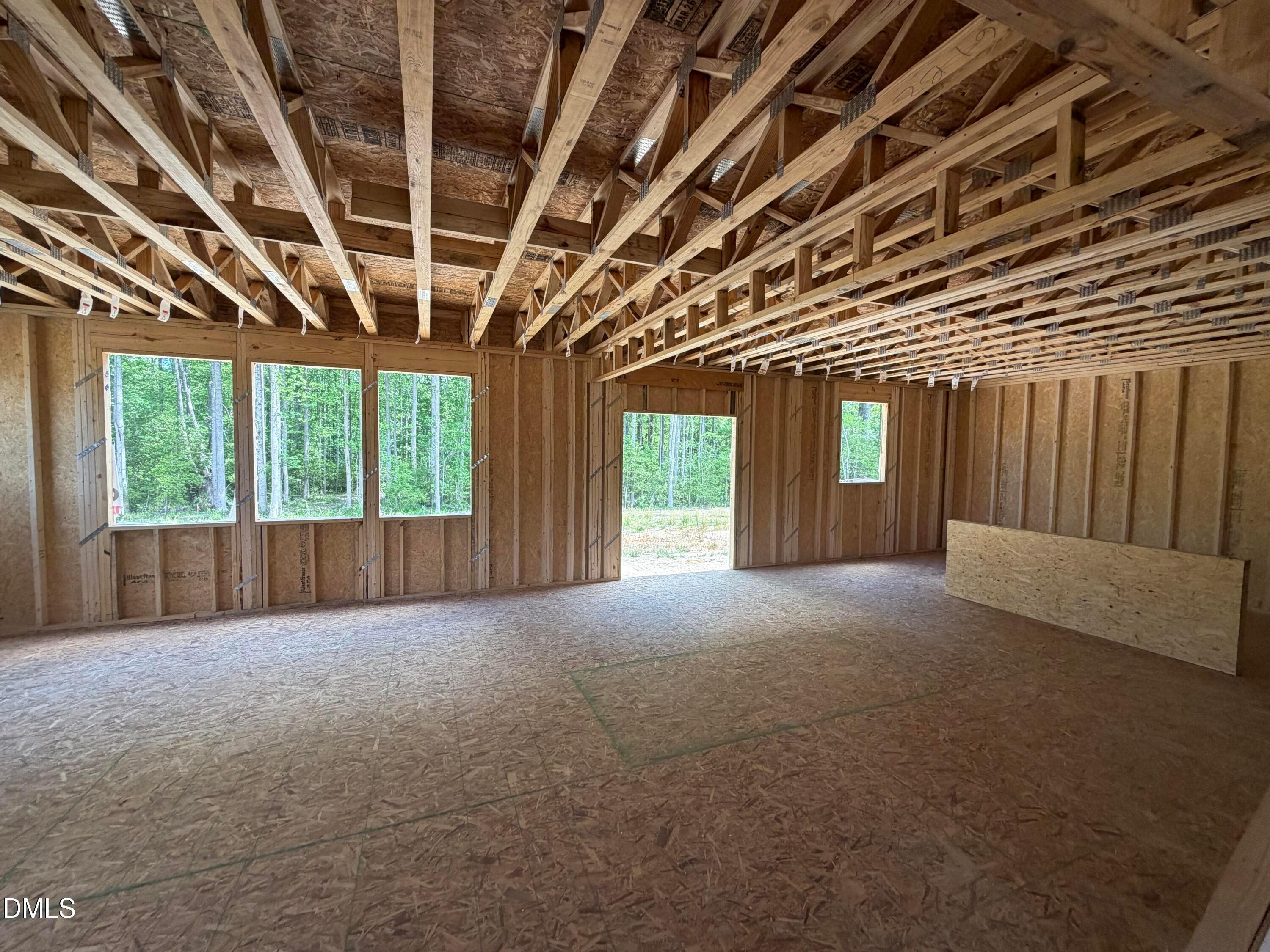 Framed two-car garage interior with OSB walls, exposed beams, large windows to woods in Davidson Homes The Hickory II C, Lillington NC
