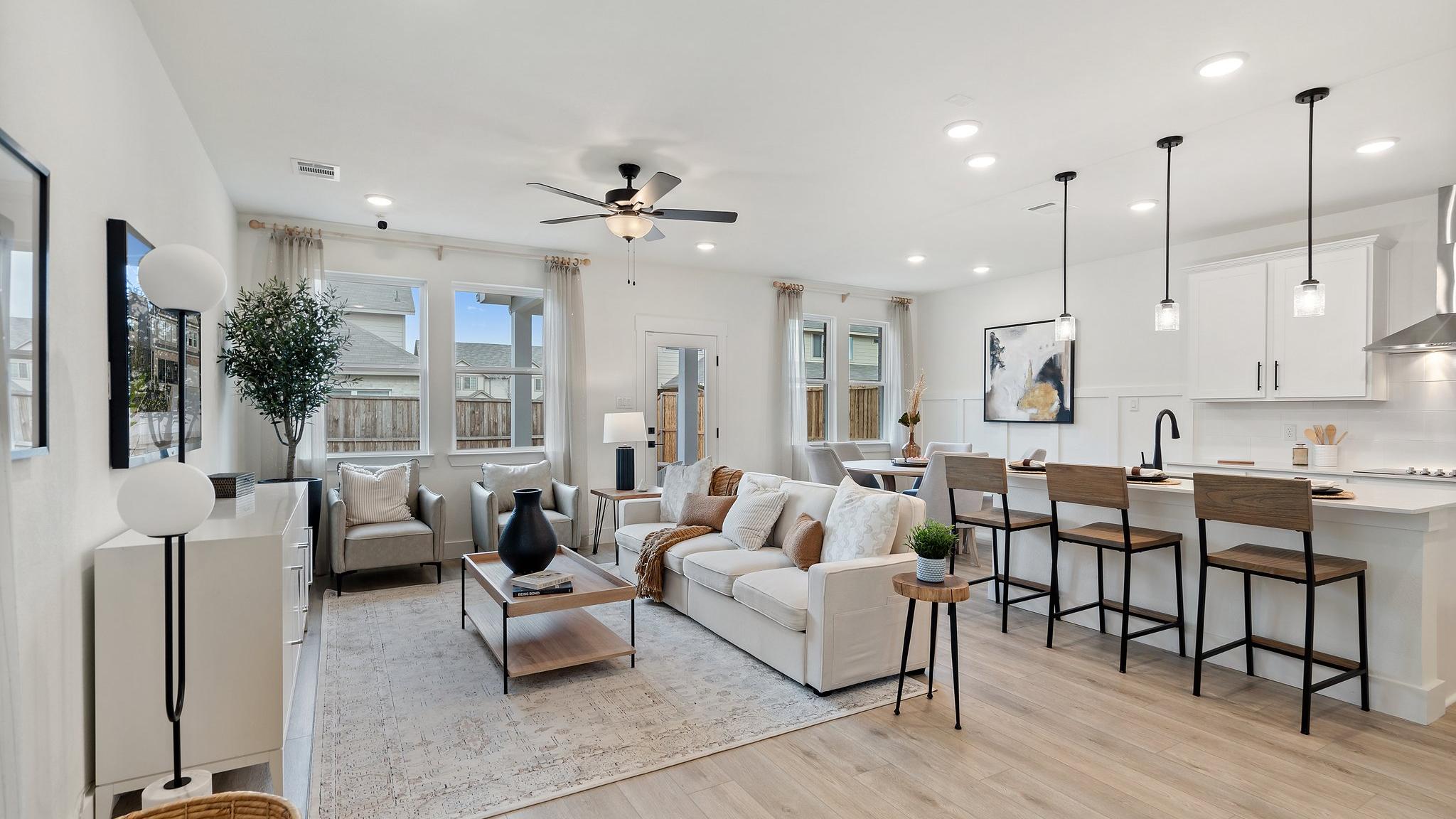 Open-concept living room and kitchen at Lake Park Villas in Wylie Texas with white sofa, hardwood floors, ceiling fan, and bar island
