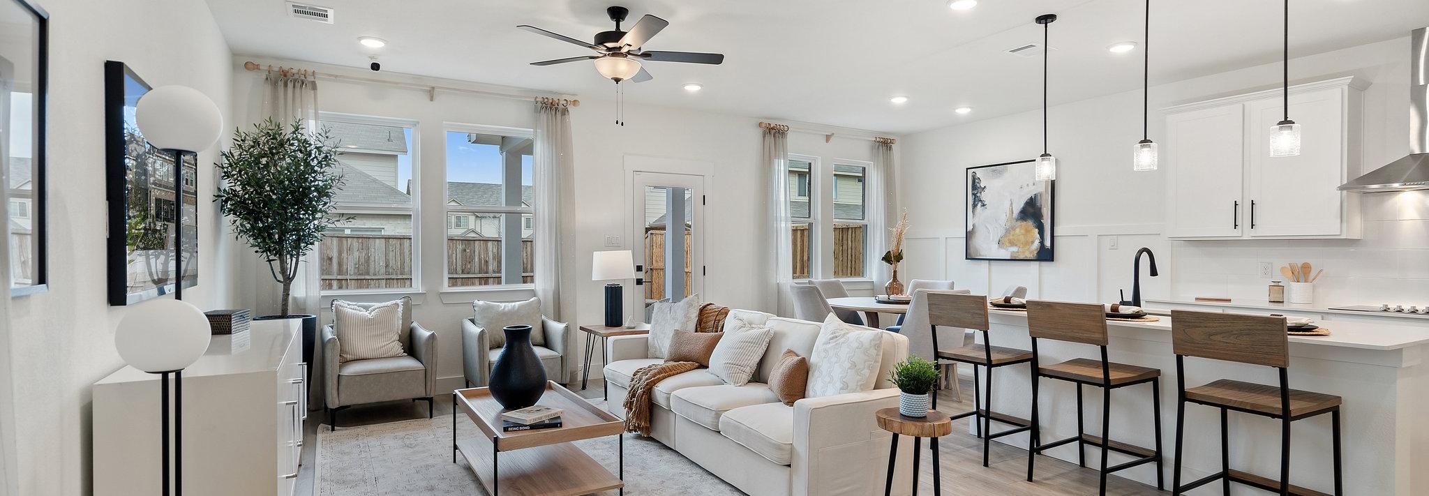 Open-concept living room and kitchen at Lake Park Villas in Wylie Texas with white sofa, hardwood floors, ceiling fan, and bar island