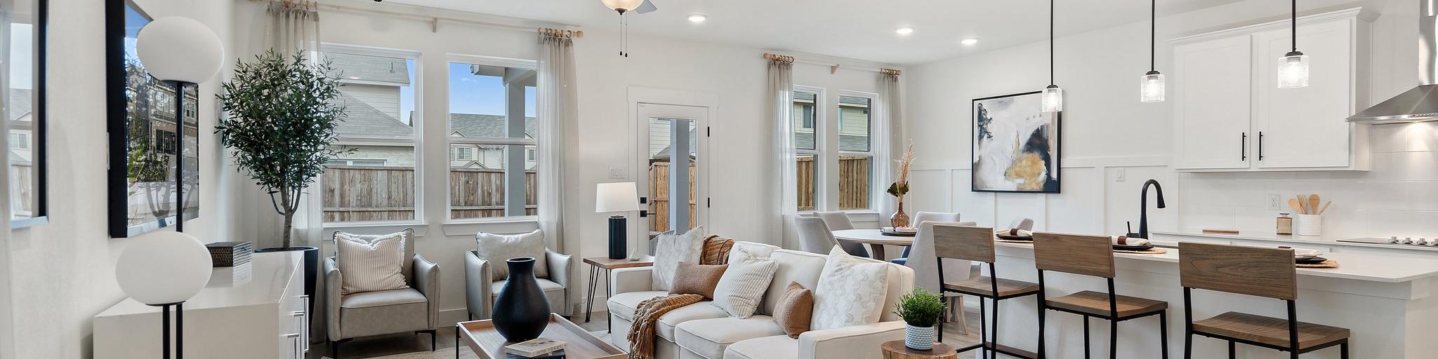 Open-concept living room and kitchen at Lake Park Villas in Wylie Texas with white sofa, hardwood floors, ceiling fan, and bar island
