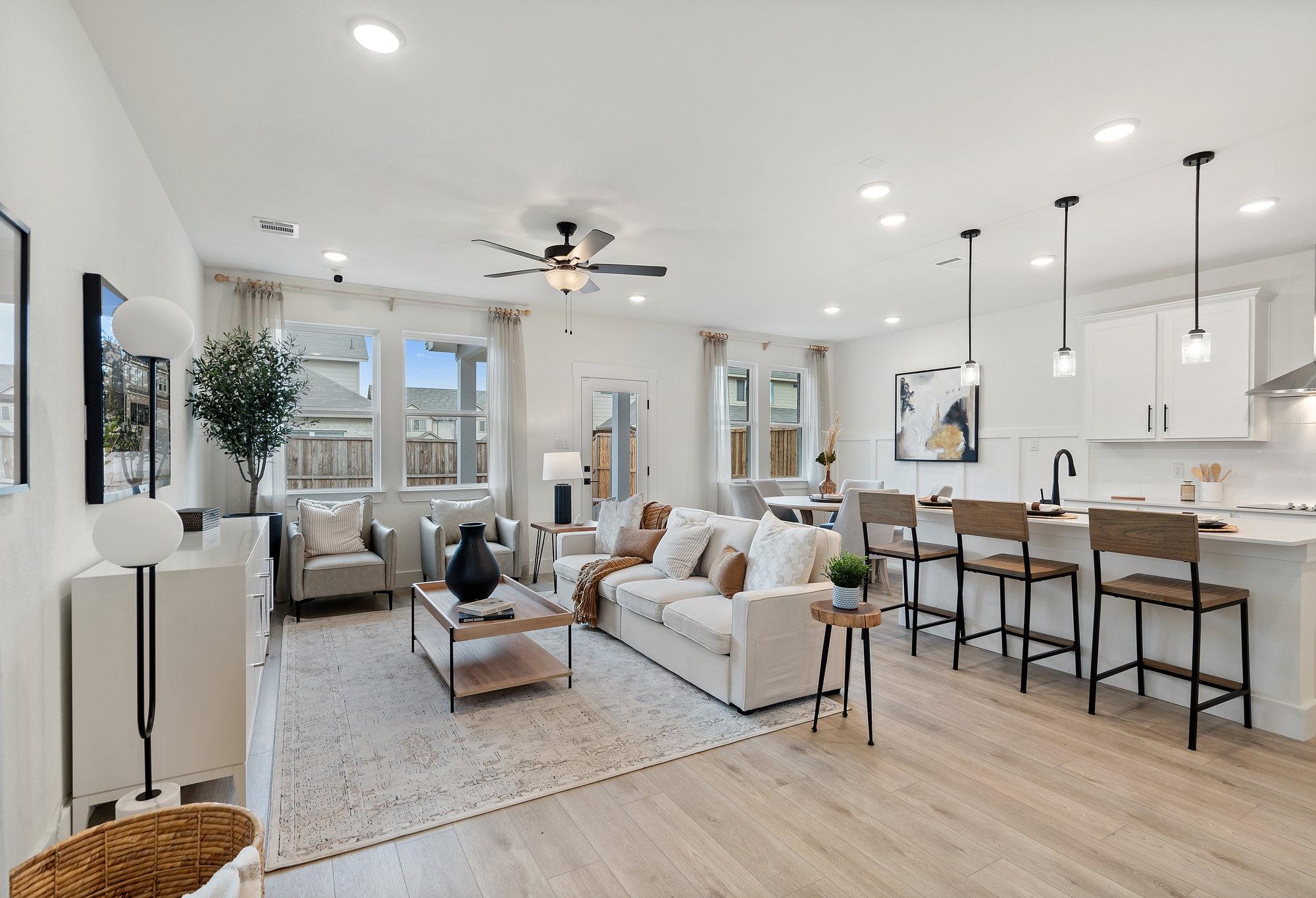Open-concept living room and kitchen in The Wake C featuring white sofa, bar island, pendant lights, and hardwood floors