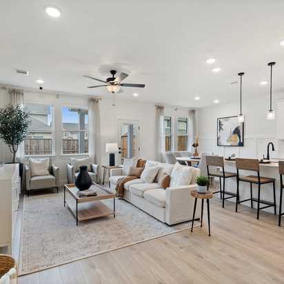 Open-concept living room and kitchen at Lake Park Villas in Wylie Texas with white sofa, hardwood floors, ceiling fan, and bar island