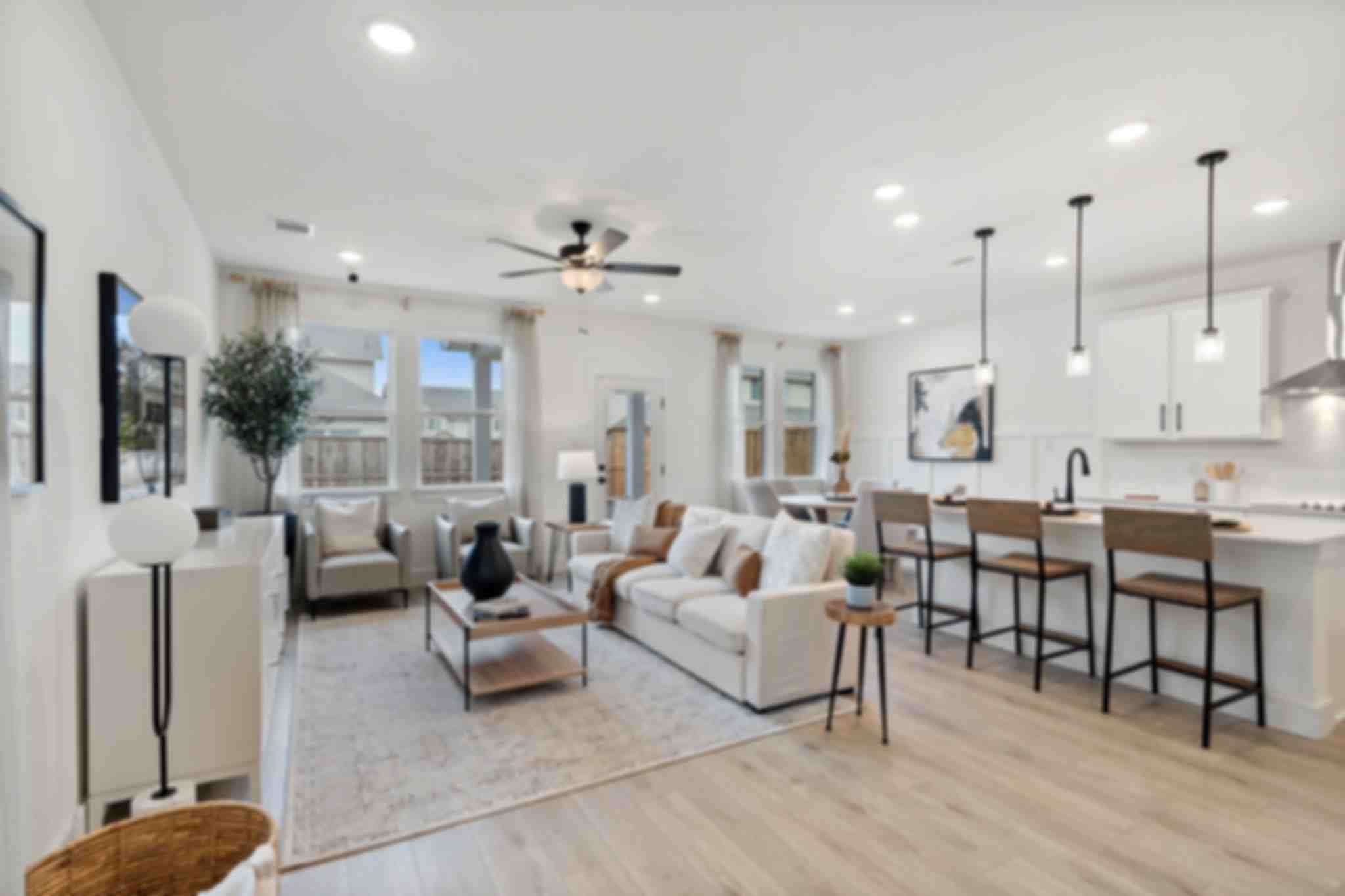 Open-concept living room and kitchen at Lake Park Villas in Wylie Texas with white sofa, hardwood floors, ceiling fan, and bar island