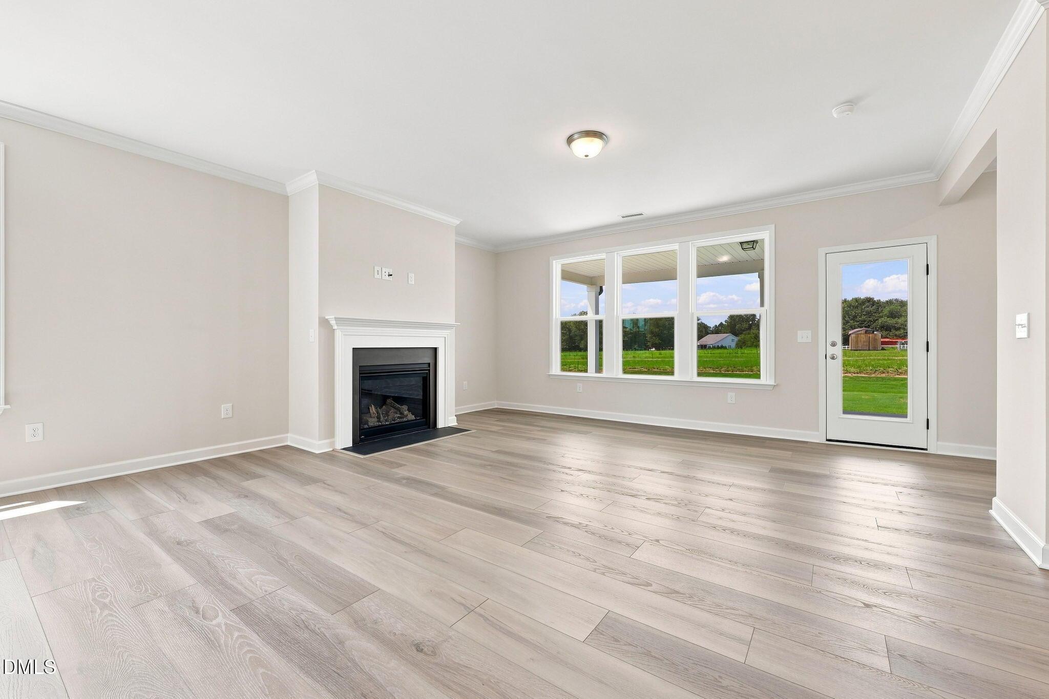 Bright living room with fireplace and wood-look floors in The Magnolia B floor plan at Retreat at North Main, Lillington.