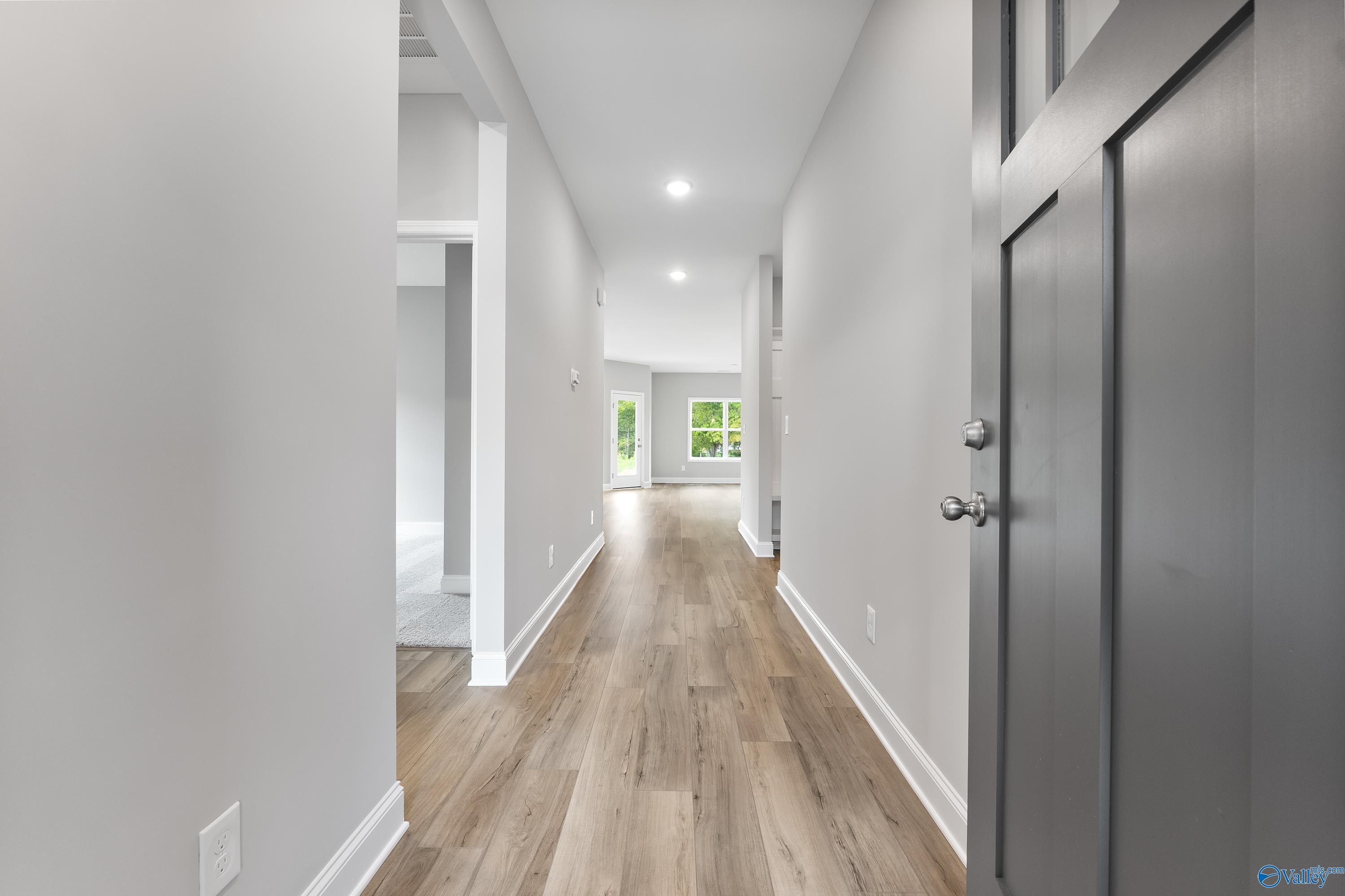 Bright hallway with light hardwood floors, white walls, and modern doors in Davidson Homes The Franklin C, Huntsville AL