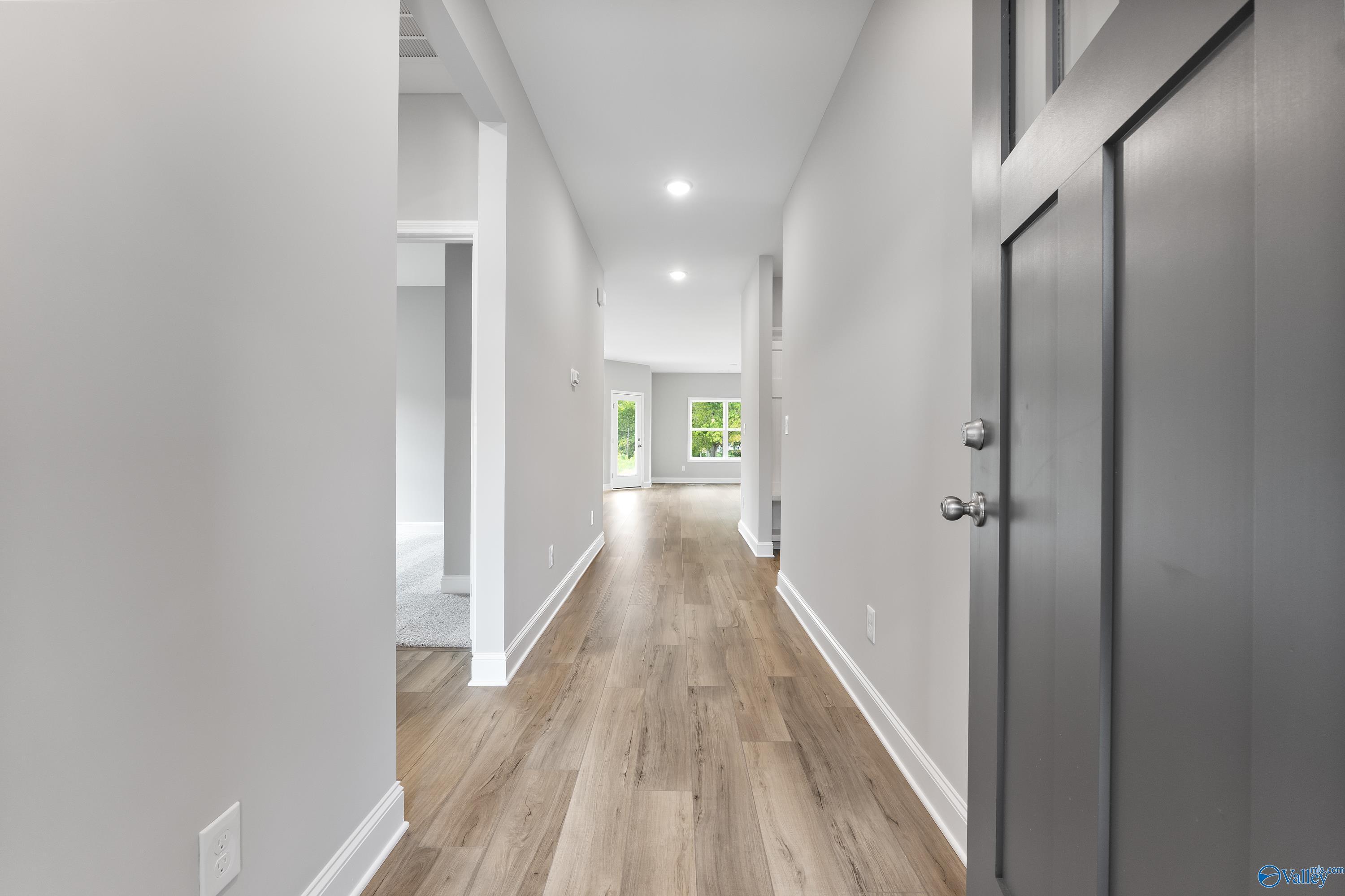 Bright hallway with light hardwood floors, white walls, and modern doors in Davidson Homes The Franklin C, Huntsville AL