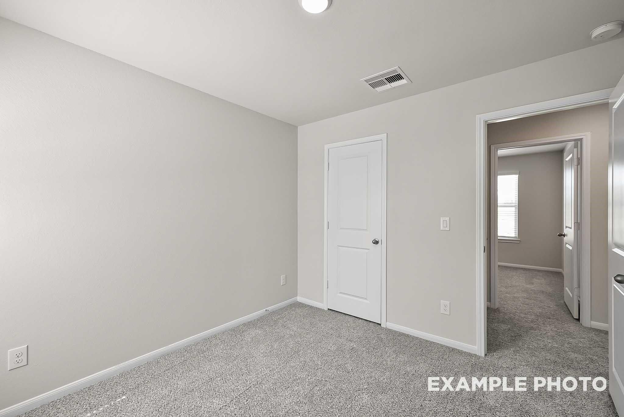 Spacious secondary bedroom with neutral carpet and closet in The Blanco F floor plan at Spring Branch Crossing, Conroe.
