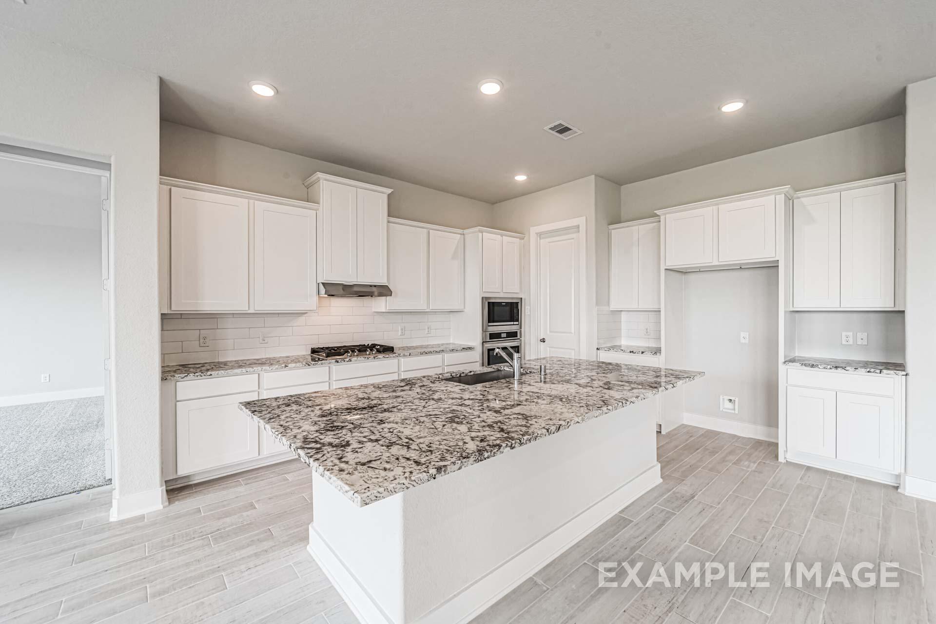 Spacious gourmet kitchen in The George A with white shaker cabinets, granite island sink, and stainless appliances