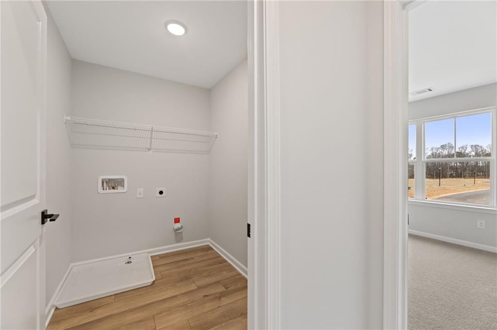 Bright laundry room with utility sink, washer/dryer hookups, and hanging rod in Davidson Homes The Rabun C, Cedar Farms, Winder, Georgia