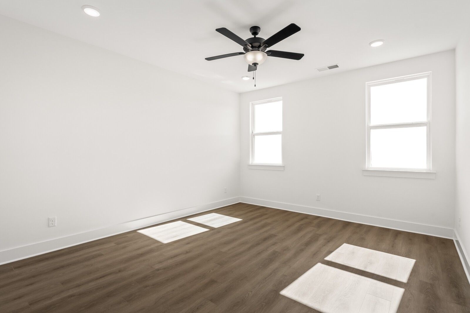 Bright bedroom with white walls, two large windows, ceiling fan, and light wood floors in Davidson Homes The Ash A, Gallatin TN
