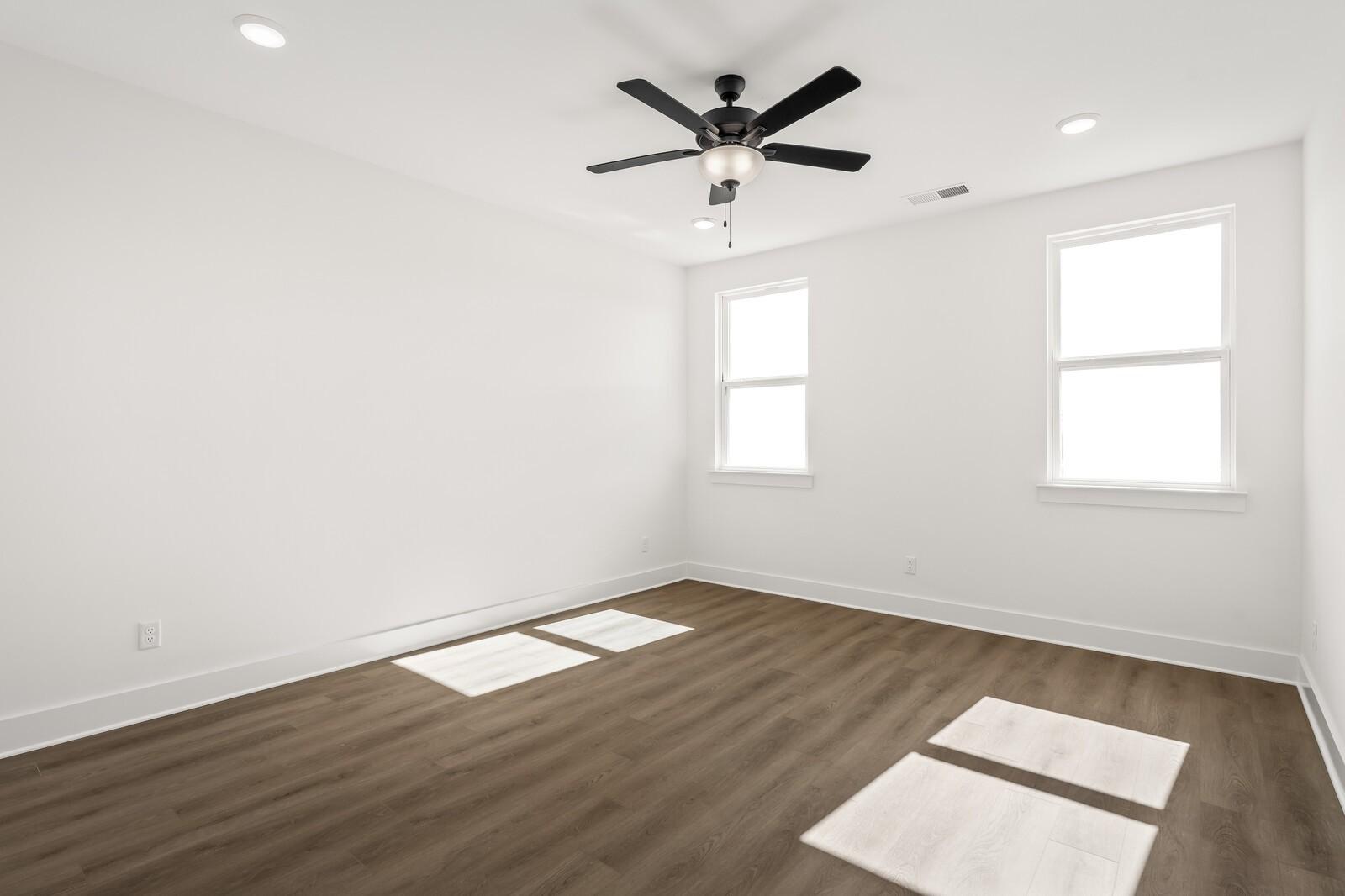 Bright bedroom with white walls, two large windows, ceiling fan, and light wood floors in Davidson Homes The Ash A, Gallatin TN