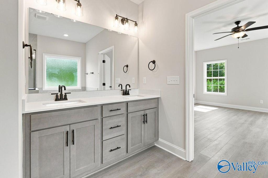 Dual vanity bathroom with gray cabinets, large mirror, and luxury vinyl plank flooring in Davidson Homes' The Rockford, Hartselle, Alabama