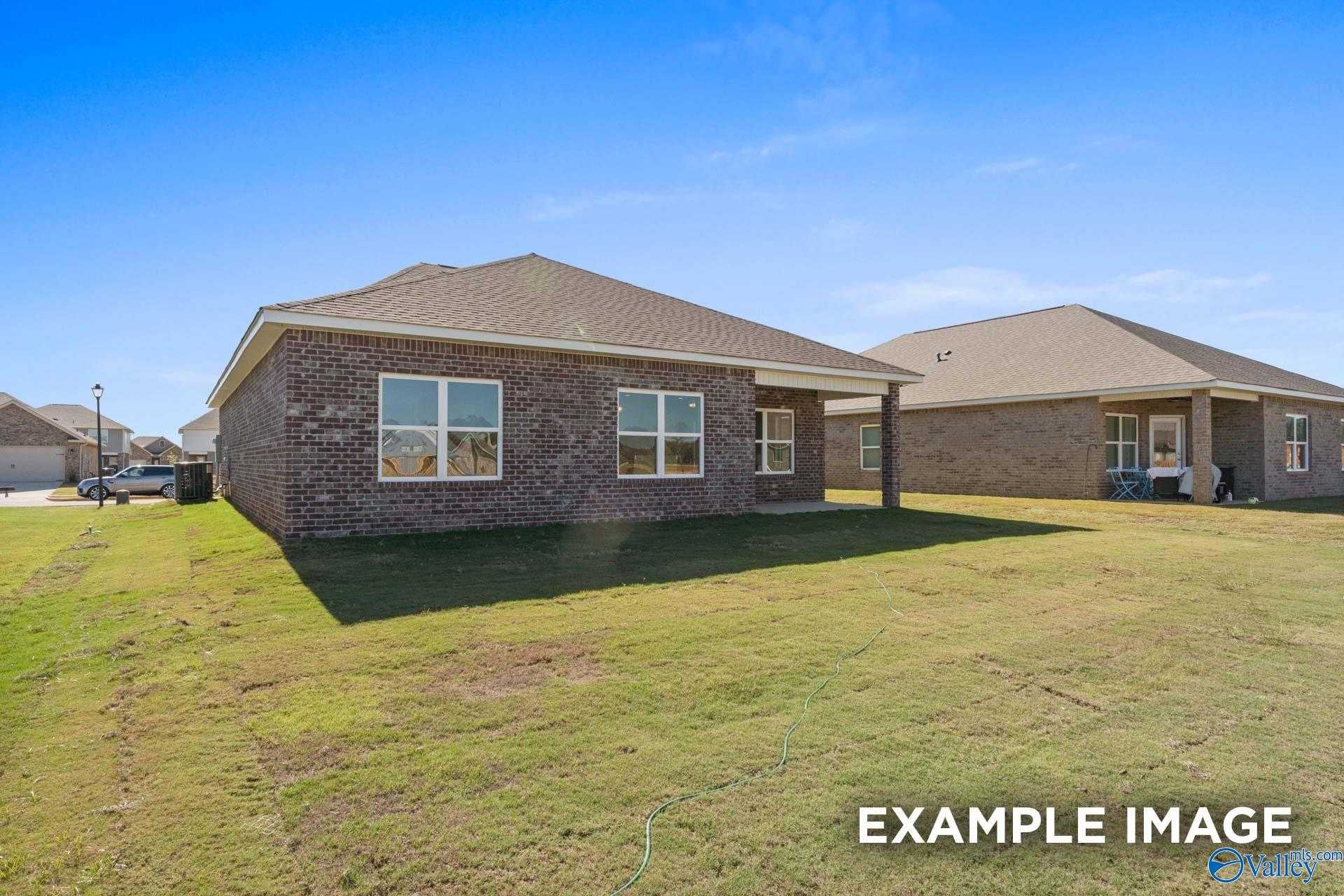 Brick single-story home with 2-car garage, large windows, and covered entry on green lawn in Walker's Hill, Meridianville, Alabama