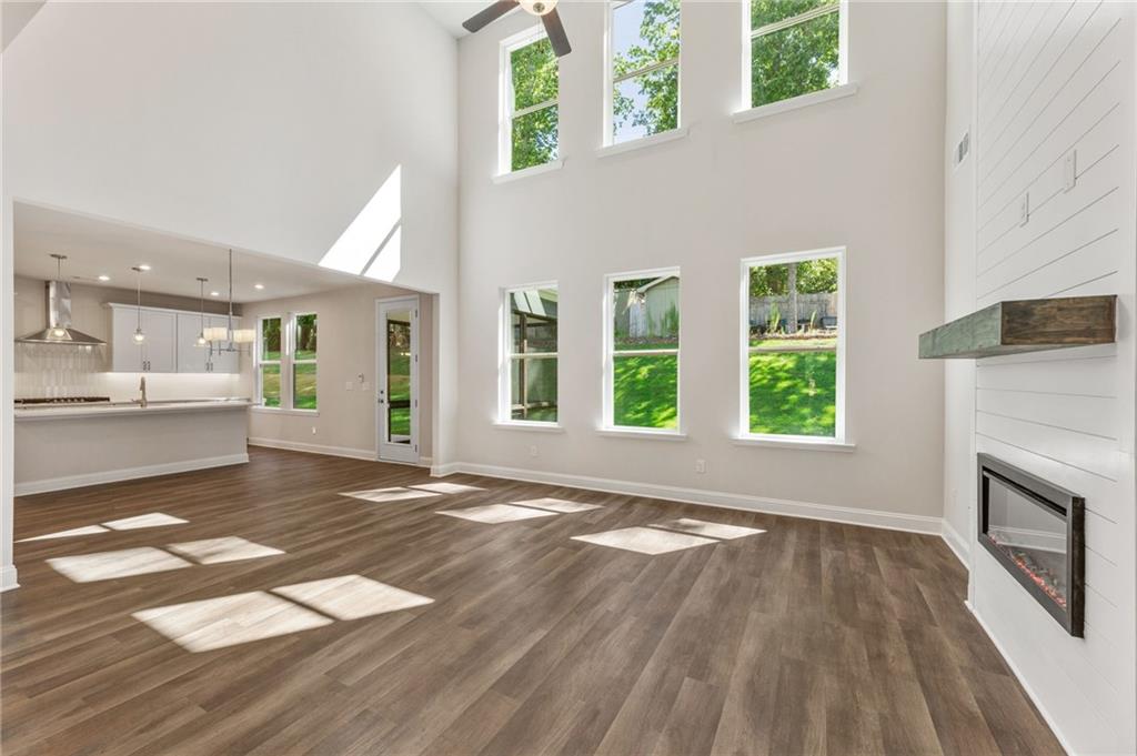 Bright great room with vaulted ceilings, large windows, gas fireplace, and open kitchen in Davidson Homes The Danbury E, Buford, GA