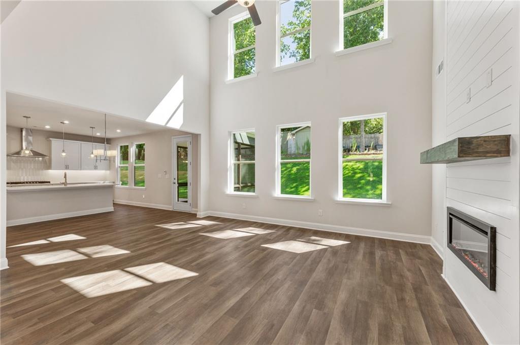 Bright open-concept great room with vaulted ceiling, shiplap walls, gas fireplace, and large windows to green backyard in Davidson Homes The Danbury E, Buford, GA