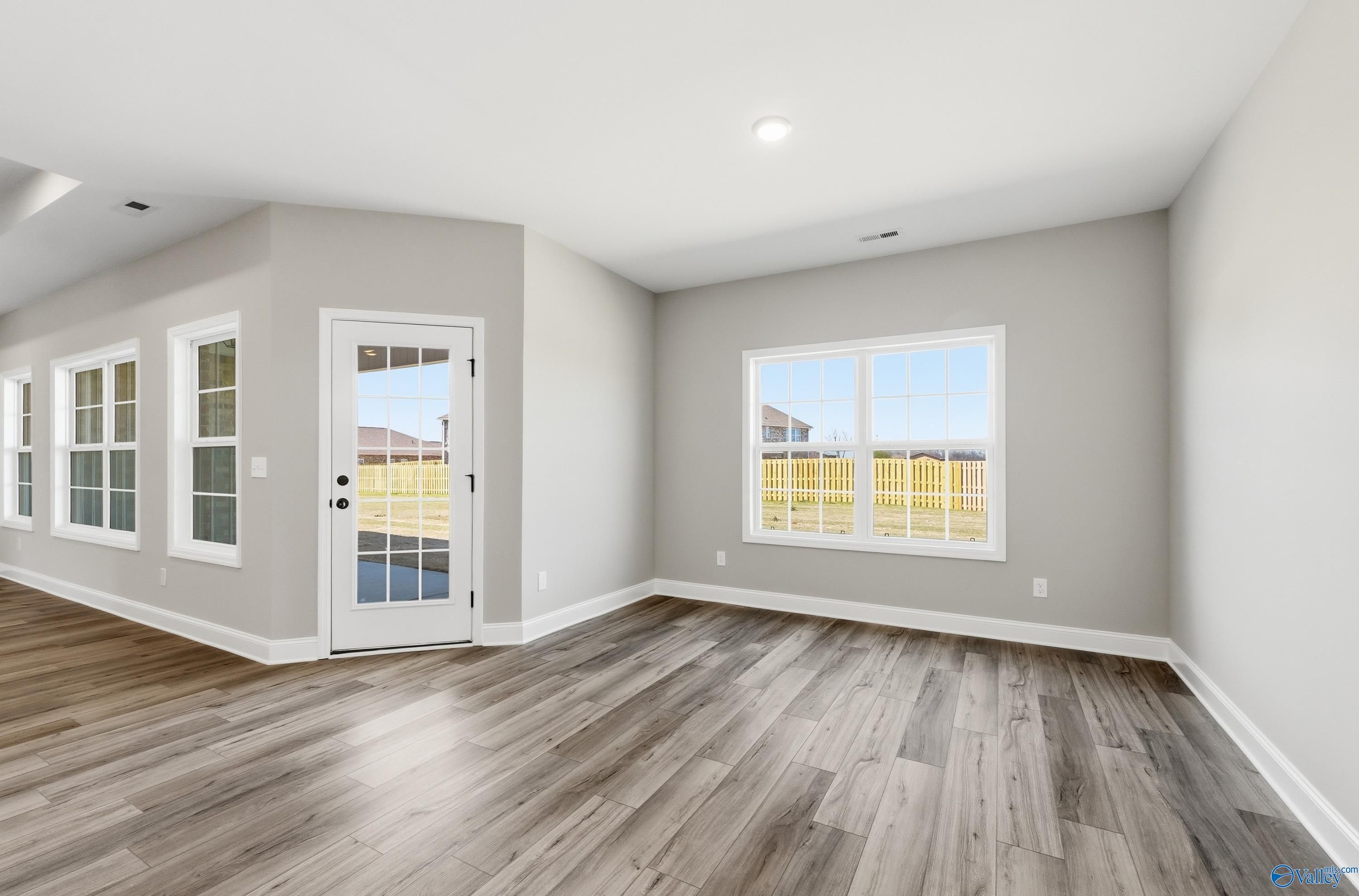 Spacious family room with gray walls, large windows, glass door to fenced backyard, and hardwood floors in Davidson Homes The Rockford, Harvest AL