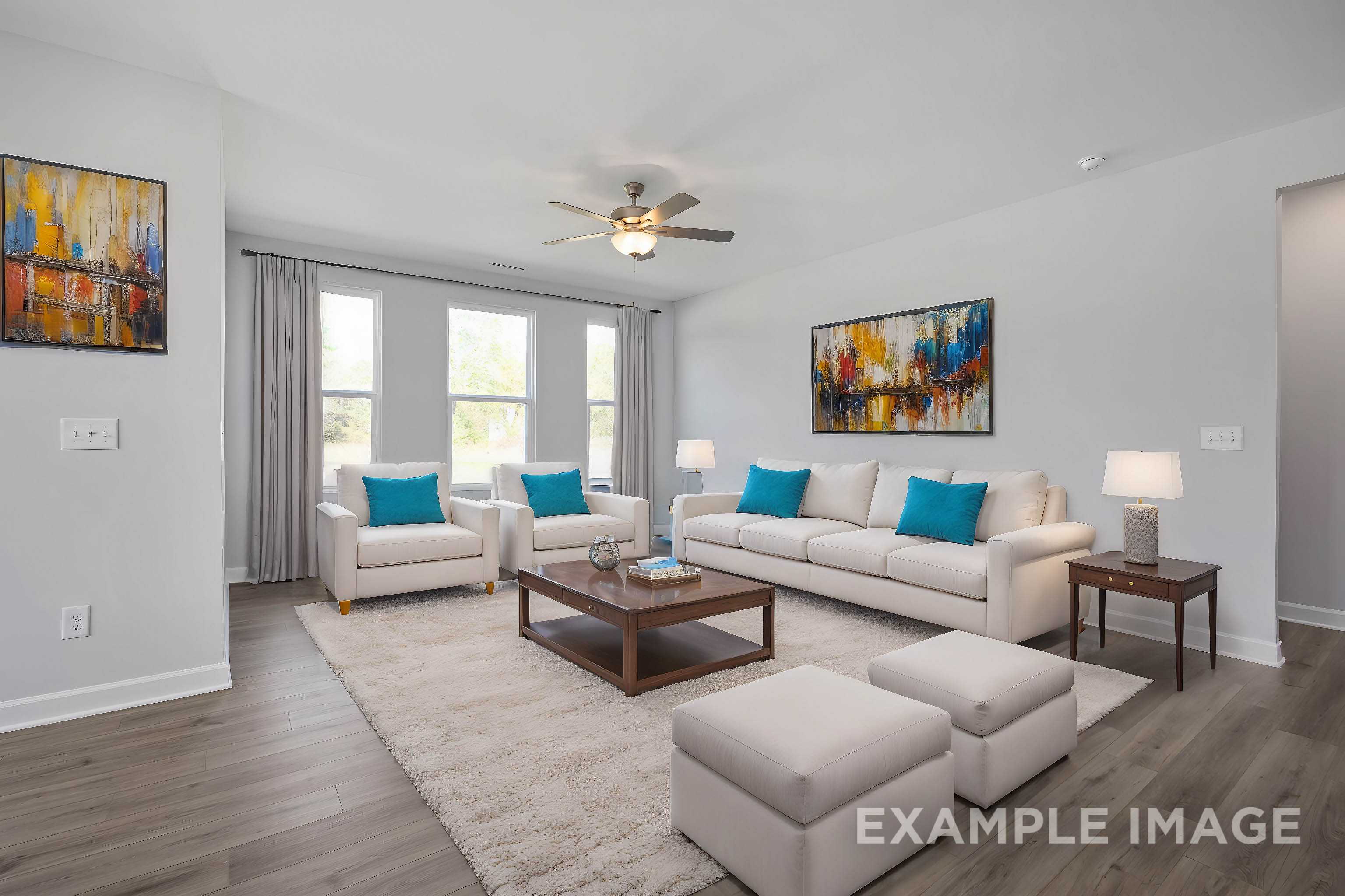 Spacious living room in The Ash home design with beige sofa and armchairs, turquoise pillows, abstract art, large windows, and hardwood floors
